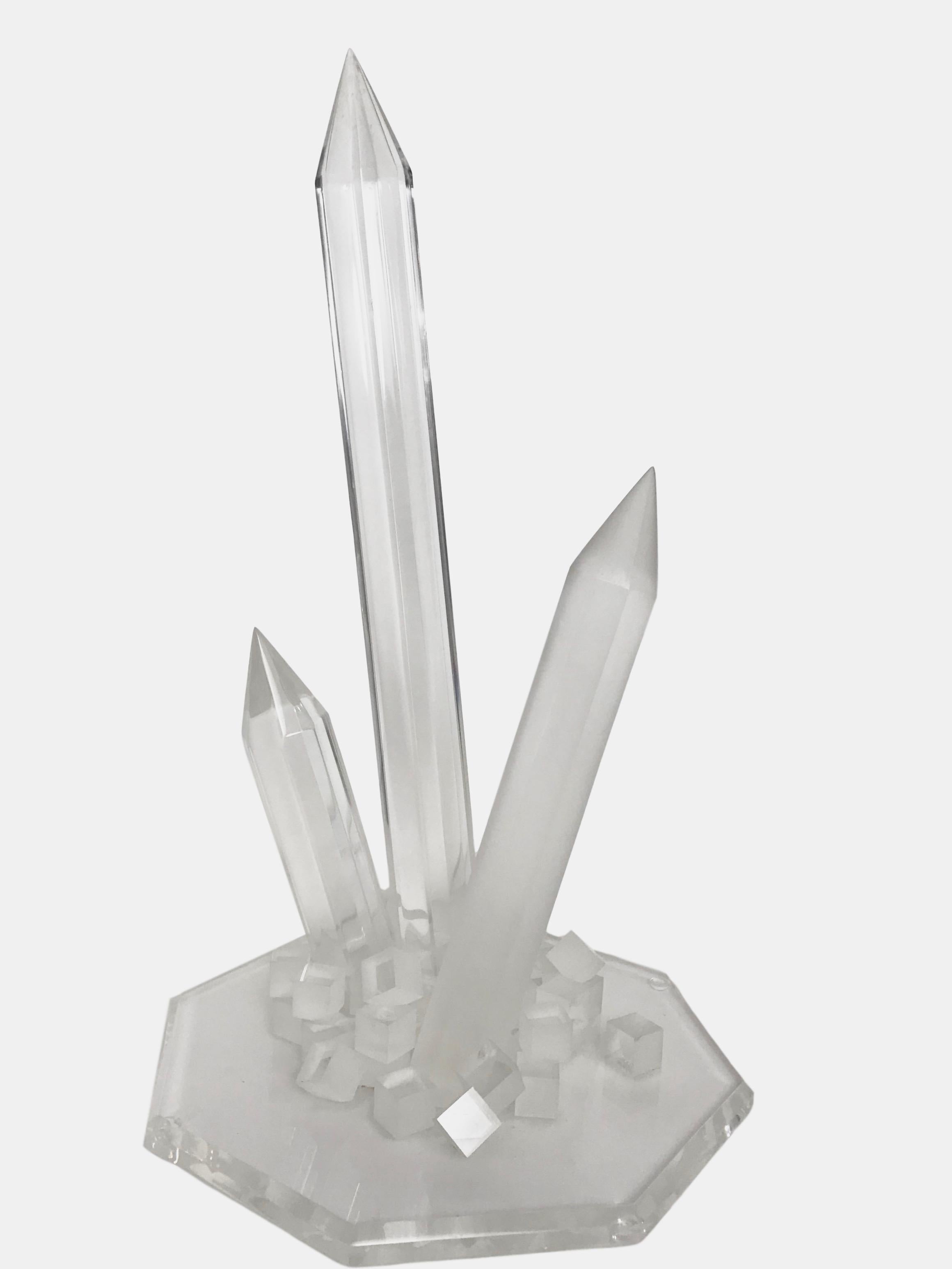 This is a Postmodern Lucite sculpture of a crystal formation on a heptagon base. Two of the crystal formations are a clear Lucite and one is a frosted Lucite.