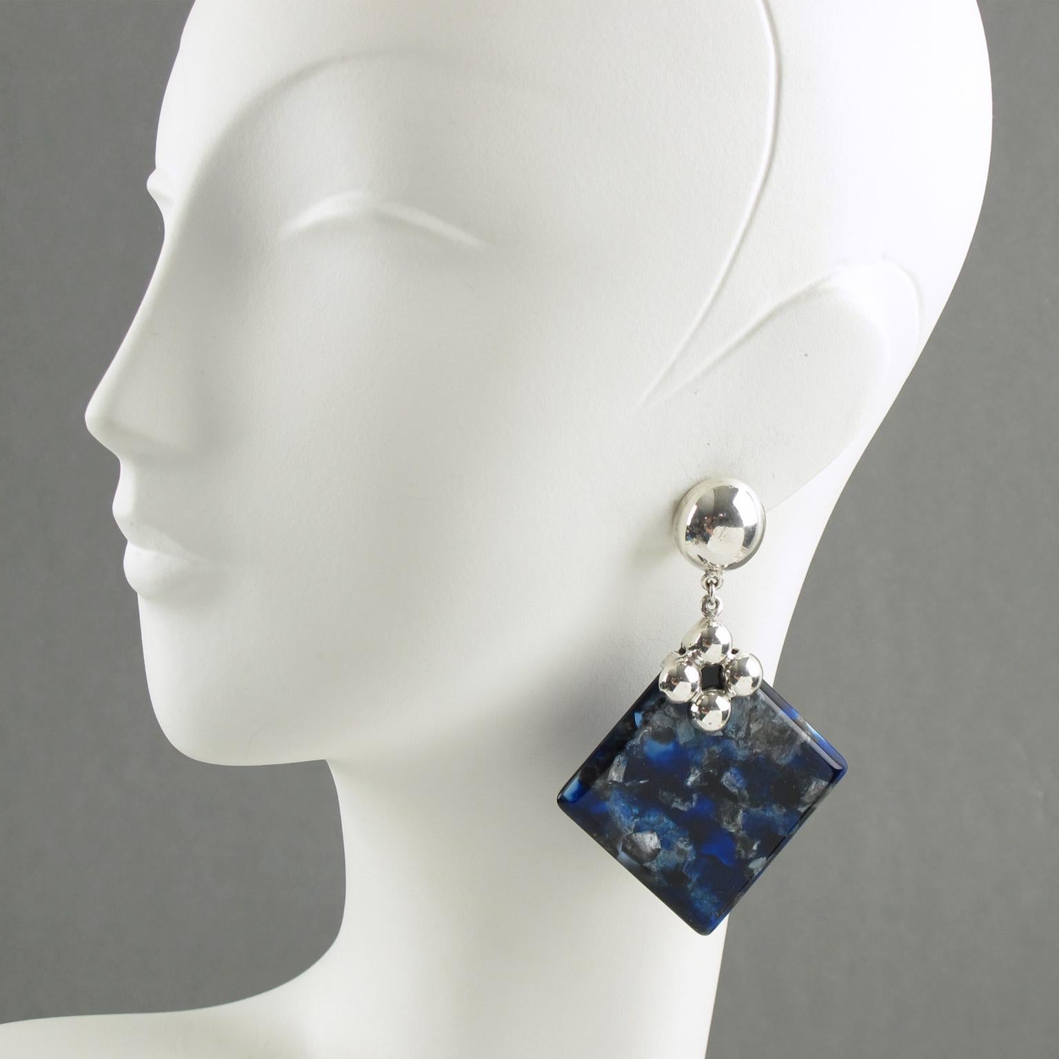 Lovely silver plate and lucite dangling clip-on earrings. Polished silver plate hardware and clip holding a thick geometric piece of lucite in incredible electric blue, black, and grey marble color with a pearlized textured pattern. There is no