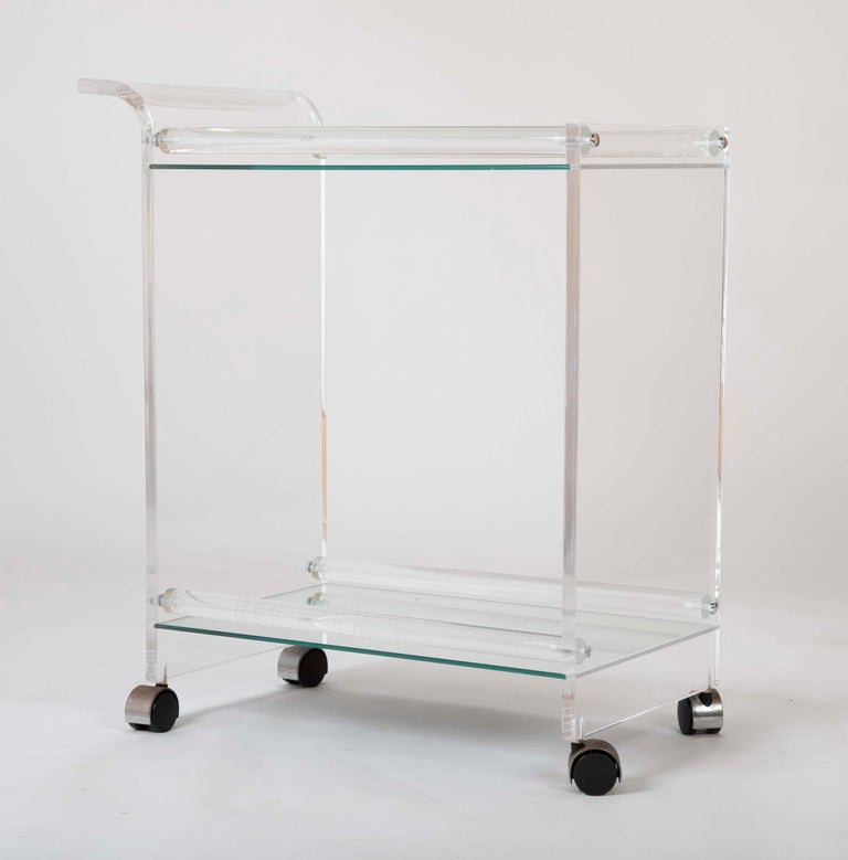 A wonderful Lucite glass tea / bar cart on wheels with mirrored shelves.