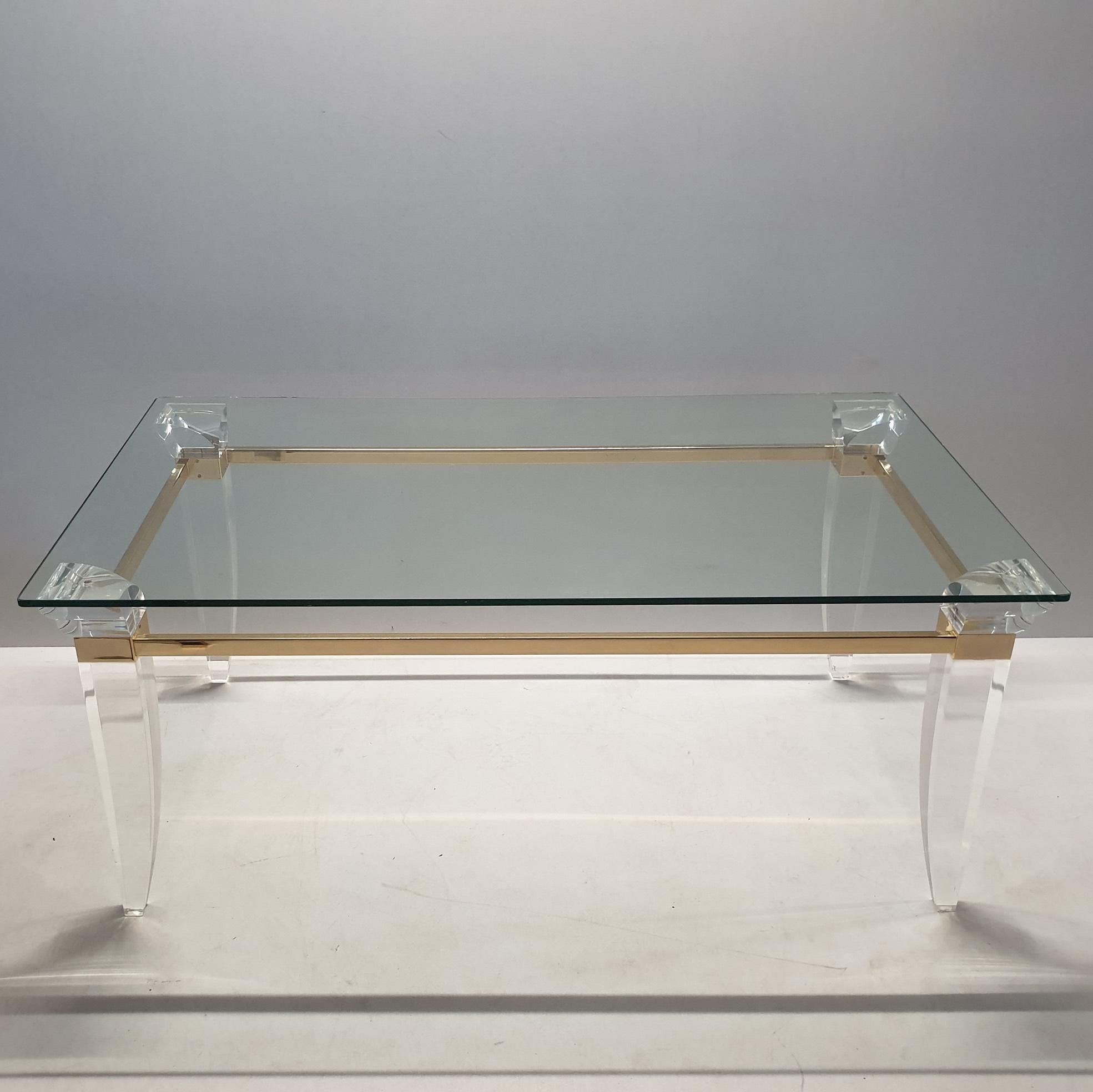 Vintage coffee table with a thick cut glass top and a gold plated frame with assymetrical lucite table legs.
In the style of Charles Hollis Jones.
Hollywood Regency.