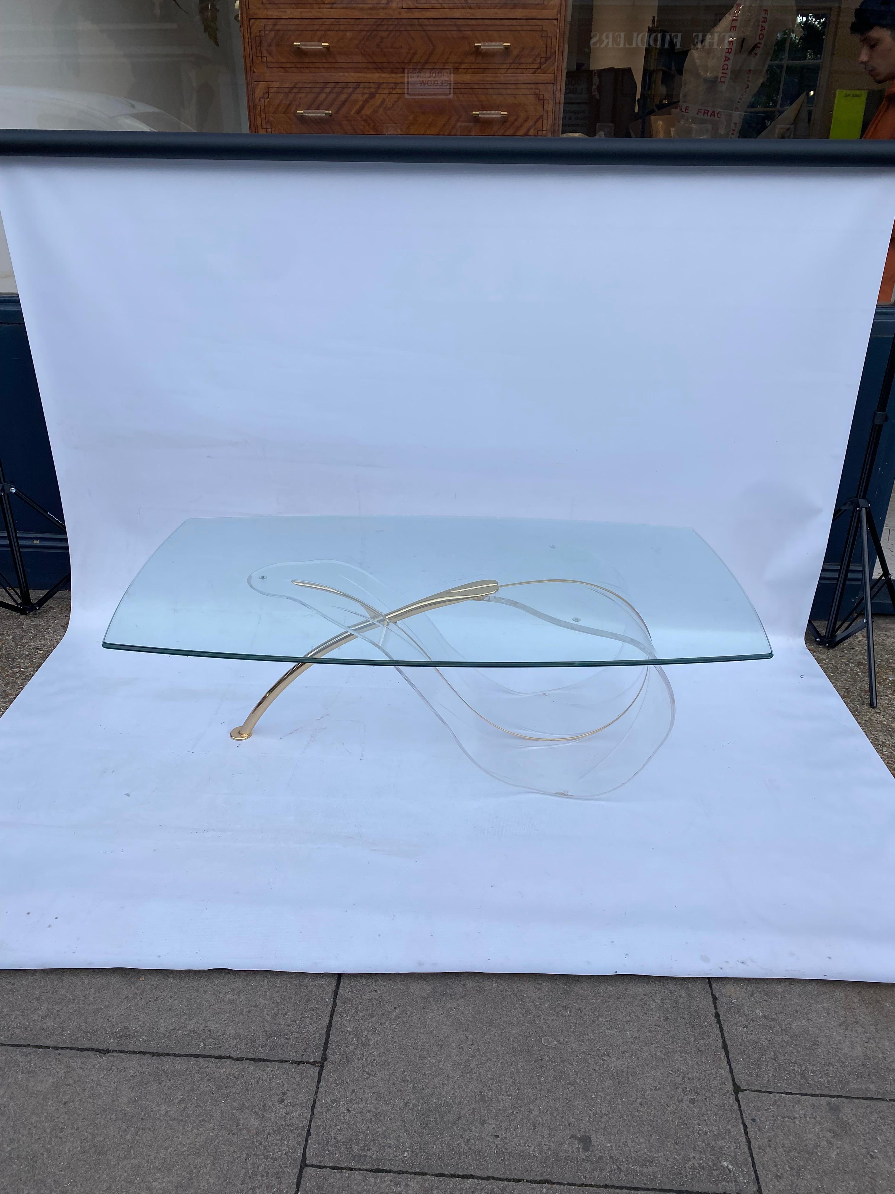 Magnifique table basse en lucite de la fin des années 1970, avec une base en forme de feuille organique.
La base est joliment façonnée pour représenter une feuille avec un pied en forme de branche plaqué laiton qui soutient le plateau en verre.
Le