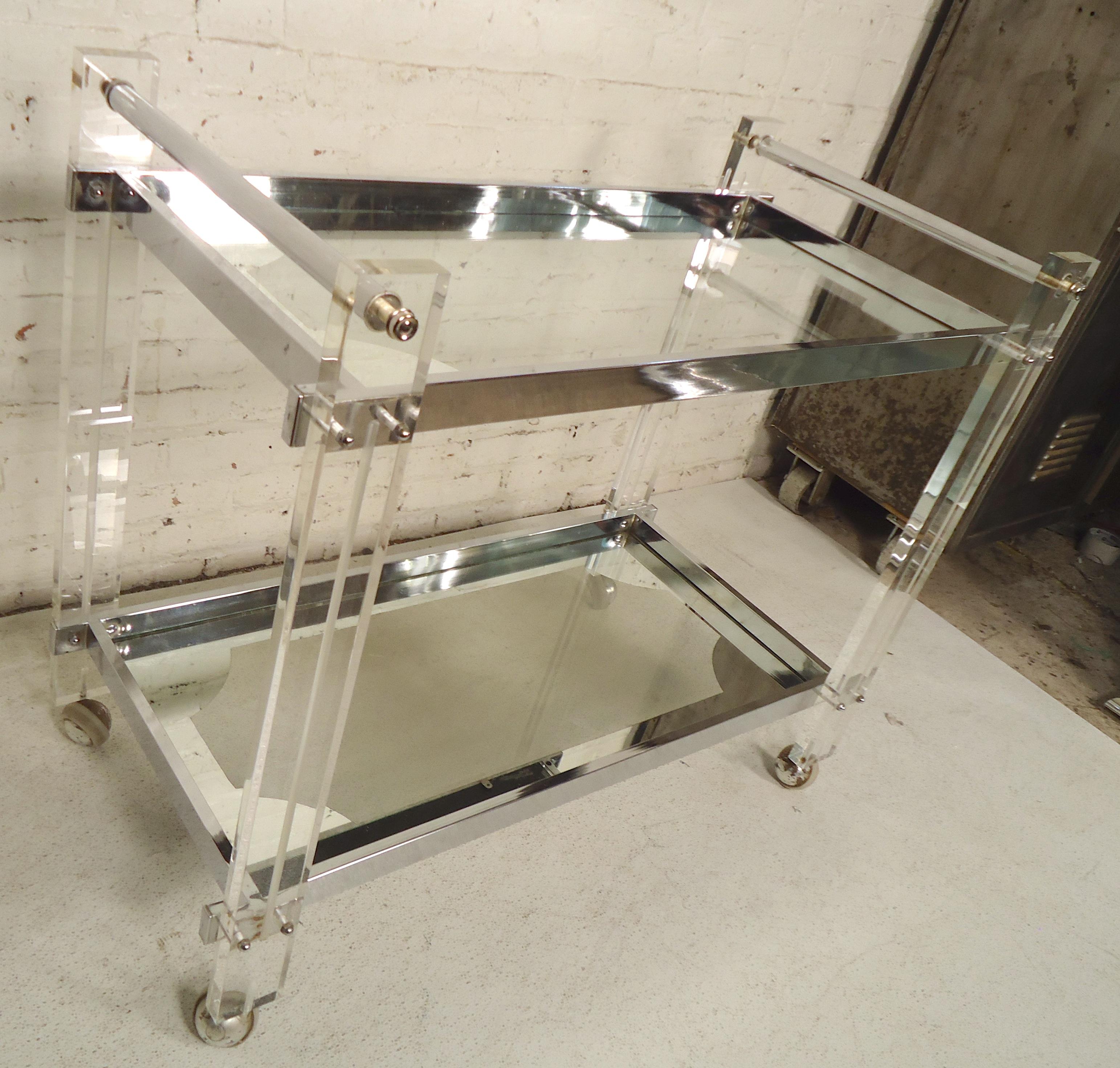 Sleek mid-century rolling cart with glass shelves and Lucite frame. Chrome trim and accenting mirrored glass.

(Please confirm item location - NY or NJ - with dealer).
   