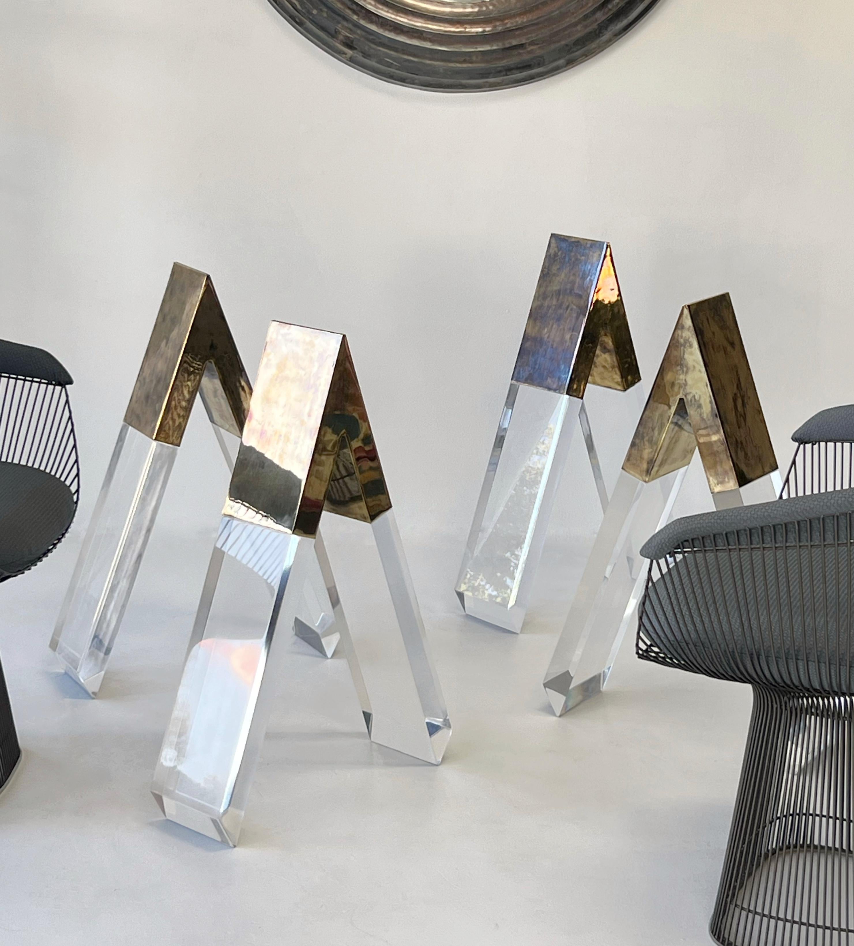 Ensemble de bases de table de salle à manger sculpturales composées d'épais pieds en Lucite facettés, coiffés d'une pièce en laiton finie à la main. Chaque base forme une silhouette architecturale en 