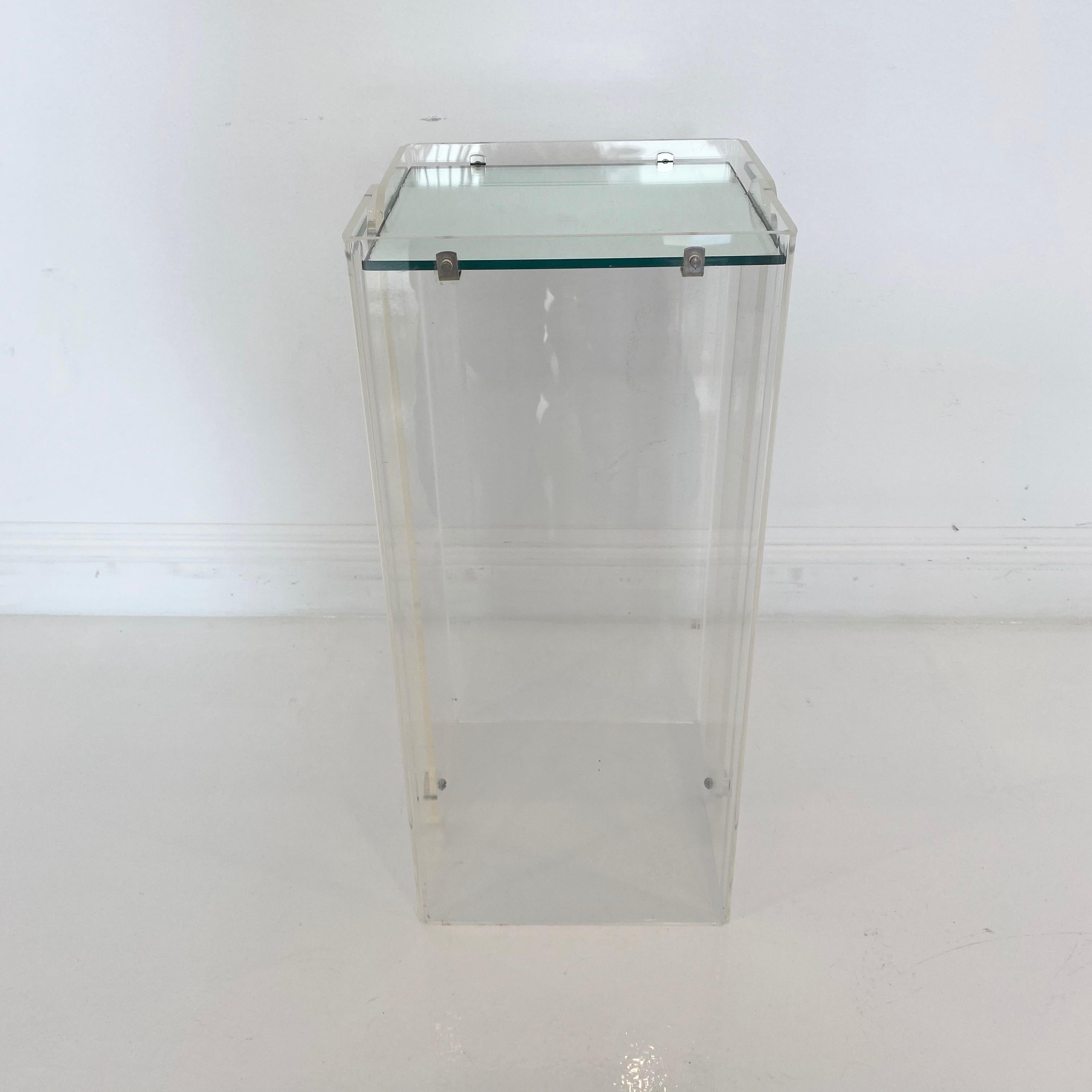 Unique pedestal made of Lucite. 2 ft tall. Clear base with flat rectangular mirror at top. Silver metal accent bolts at the top and bottom. Great accent piece and display item. Good vintage condition.