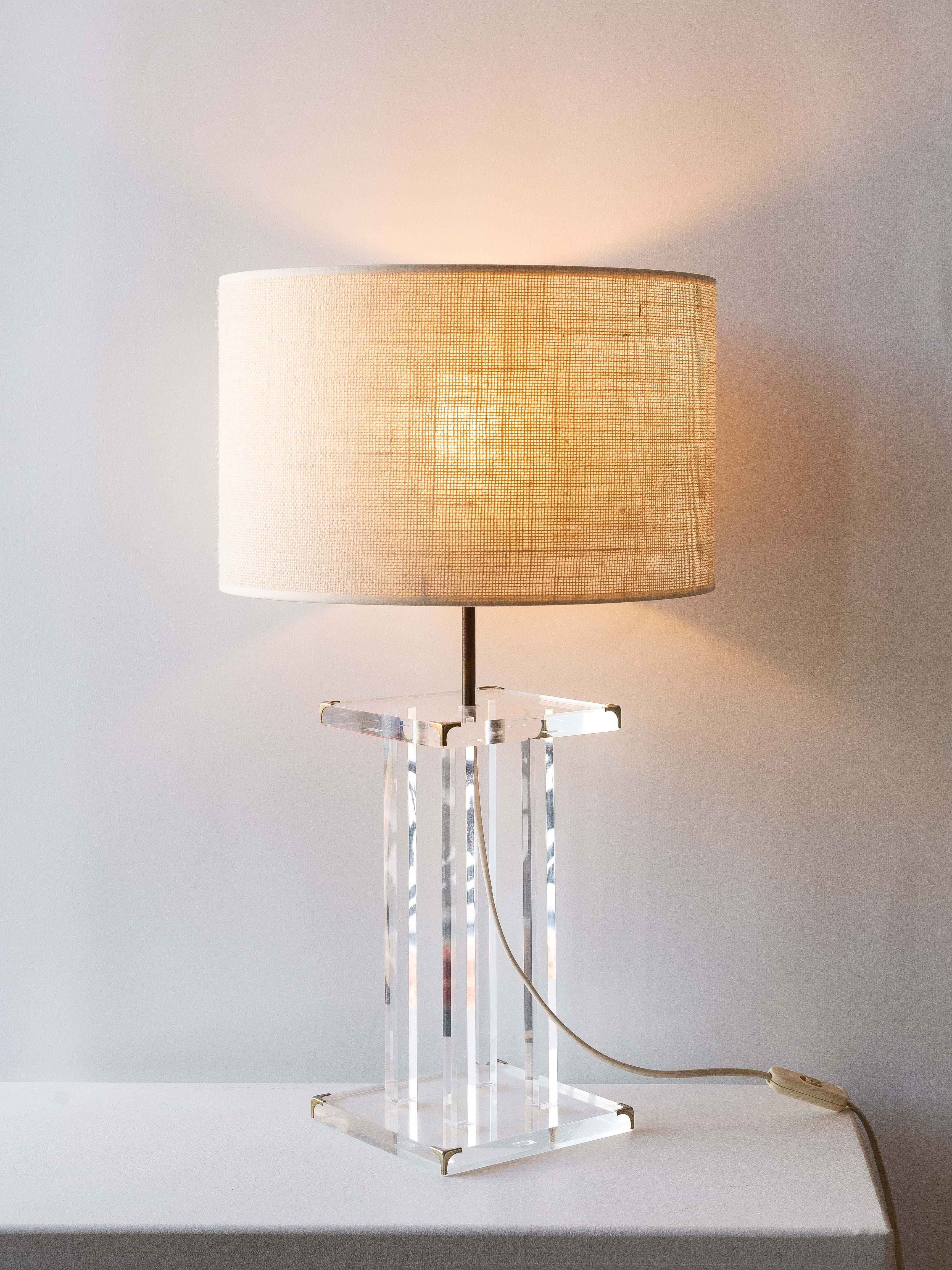 Plexiglass Table Lamp by David Lange for Roche Bobois 1970s.

The base is made of acrylic glass with four transparent legs.

Small brass corners for a chic finish are positioned on the upper and lower lucite squares.

Its minimal and transparent