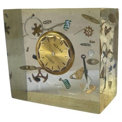 Sculpture/accroche-papier attachée à Pierre Giraudon avec pièces d'horloge en résine Lucite