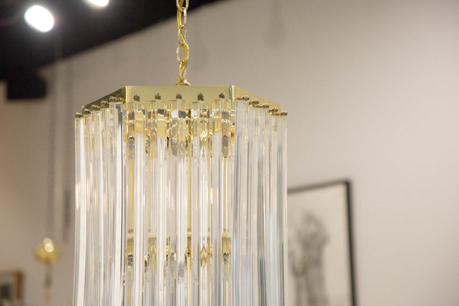 A remarkable and statement making Lucite ribbon chandelier, featuring 15 looped Lucite ribbons suspended on a brass plate frame. Accommodates 15 candelabra bulbs. 

Dimensions: 32” H x 12” D

Chain: Approx. 68” in length. 

Canopy: Included,