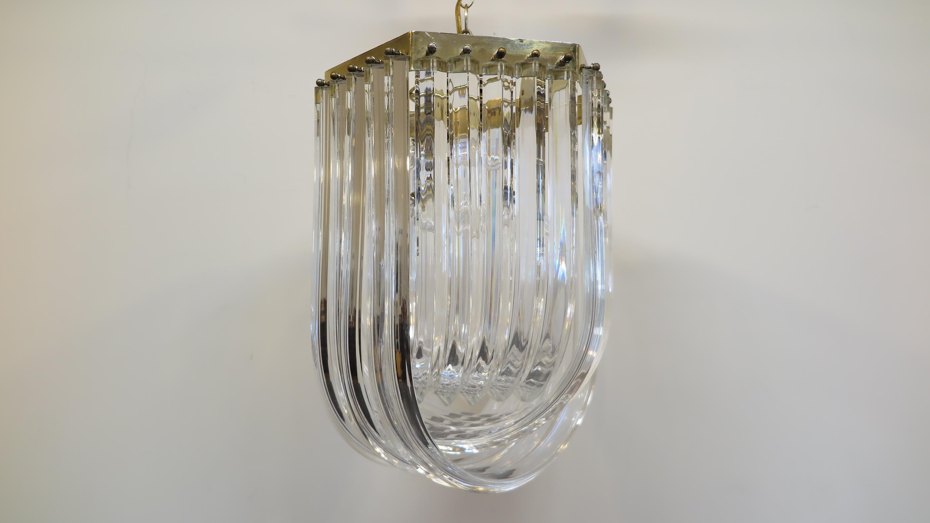 Lucite and brass pendant lamp over lapping ribbon design 1960-1970. Midcentury Lucite and brass pendant. Hollywood Regency style. Nine-light sockets provide illuminating brilliance when reflected through the arched Lucite bands. Can be mounted flush
