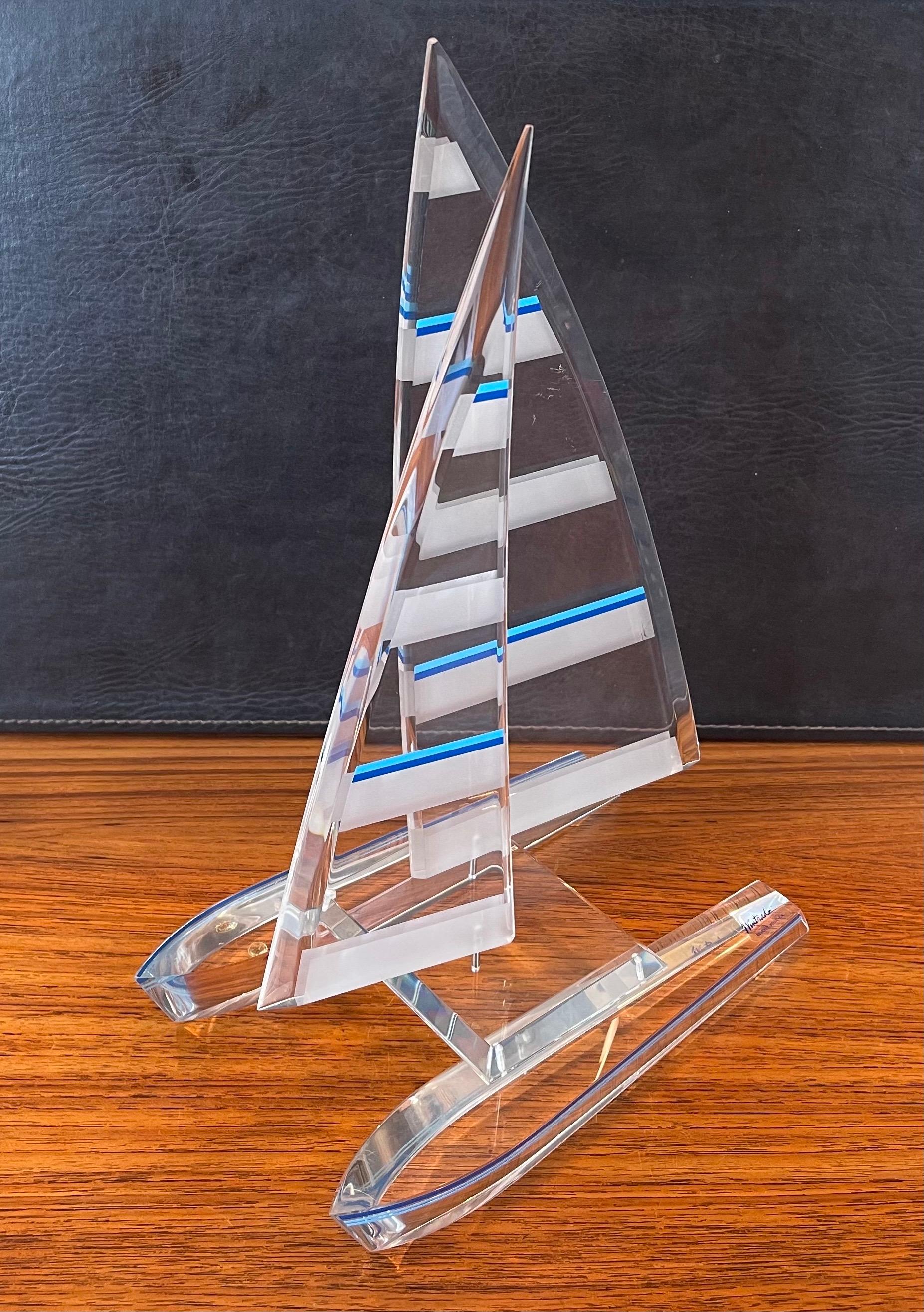 Beautiful lucite sailboat / catamaran sculpture by Wintrade of Beverly Hills, circa 2000s. This boat has two fixed hulls and two movable sails with white and blue horizontal striping. The piece is in excellent condition with no chips, cracks or