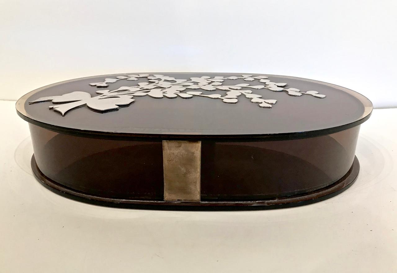 This is unusual large tortoise shell Lucite box with an applied sterling silver bouquet. The base of the box has applied silver plate decorations. This is the perfect spot to hide all of those handy desk top items--or an elegant catch-all.