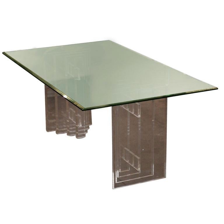This handsome dining set features a Lucite base with a beveled glass top and six matching chairs. The dual pedestal base is made up of several Lucite slabs which narrow in width as they move closer to the center of the table; each is joined together