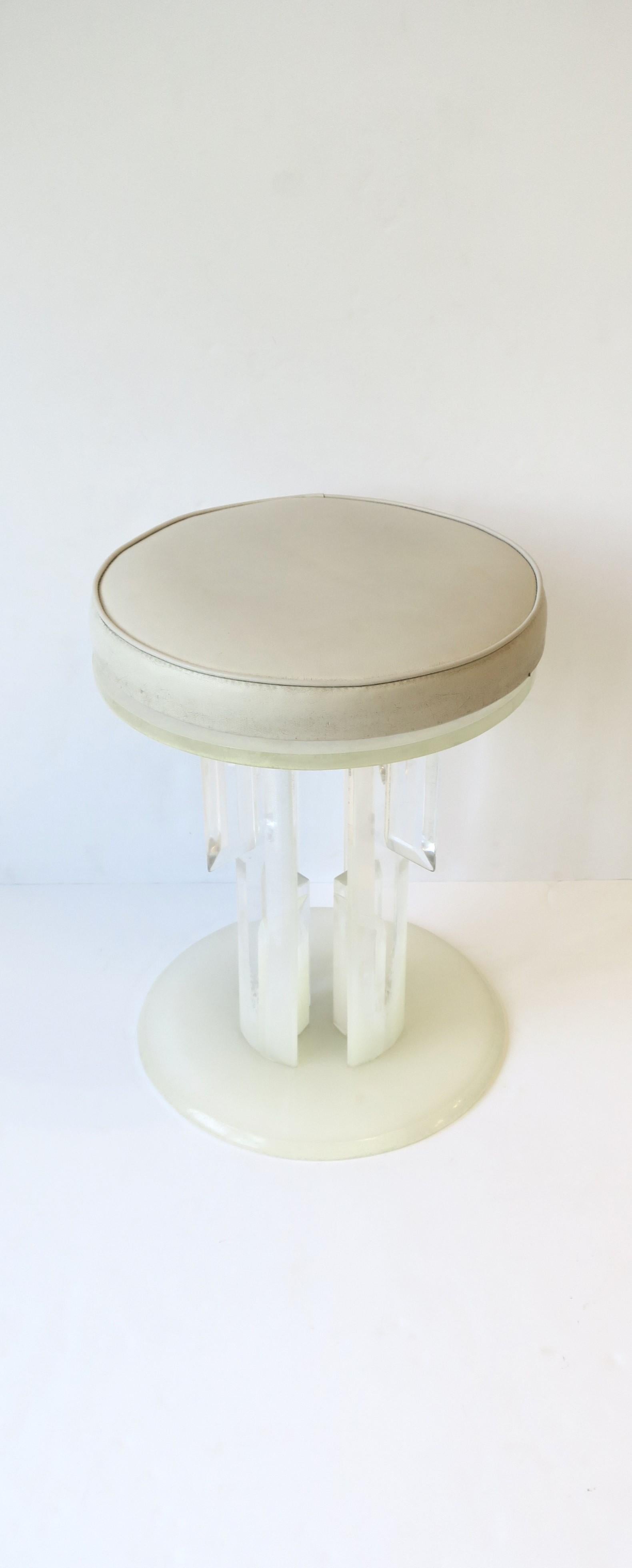 A Lucite swivel stool or vanity seat, circa 1960s - 1970s, 20th century, USA. This round swivel stool has an upholstered pleather seat cushion and a Deco/Hollywood Regency decorative Lucite base. Seat cushion can be removed for reupholstery if so
