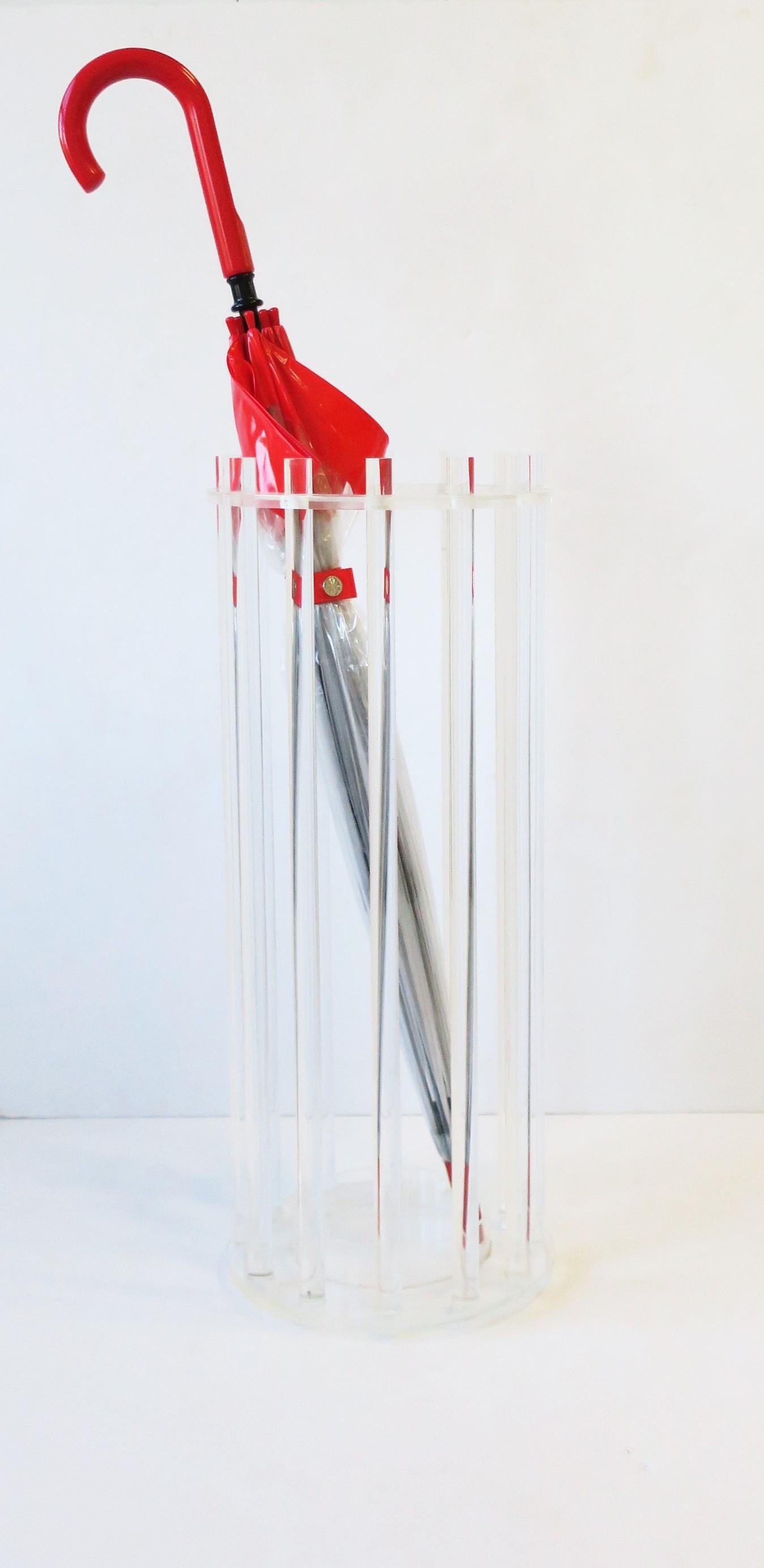 A chic Lucite umbrella holder stand, in the modern style or Postmodern period, circa late-20th century. A transparent piece that can hold tall and small umbrellas alike as shown in images. Smaller umbrellas with strap handle can hang on Lucite rods