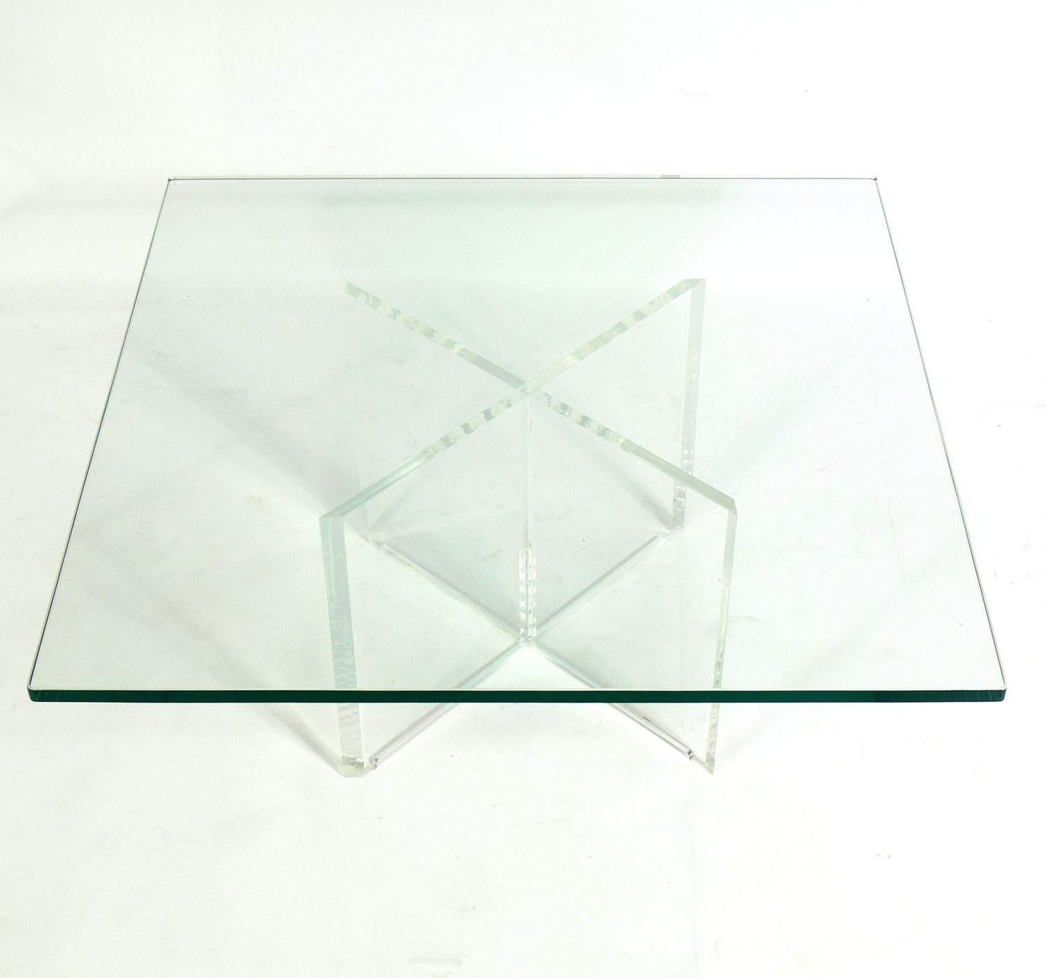 Lucite X-base coffee table, American, circa 1970s. It is well constructed with a chunky Lucite or acrylic X-form base and a thick glass top.