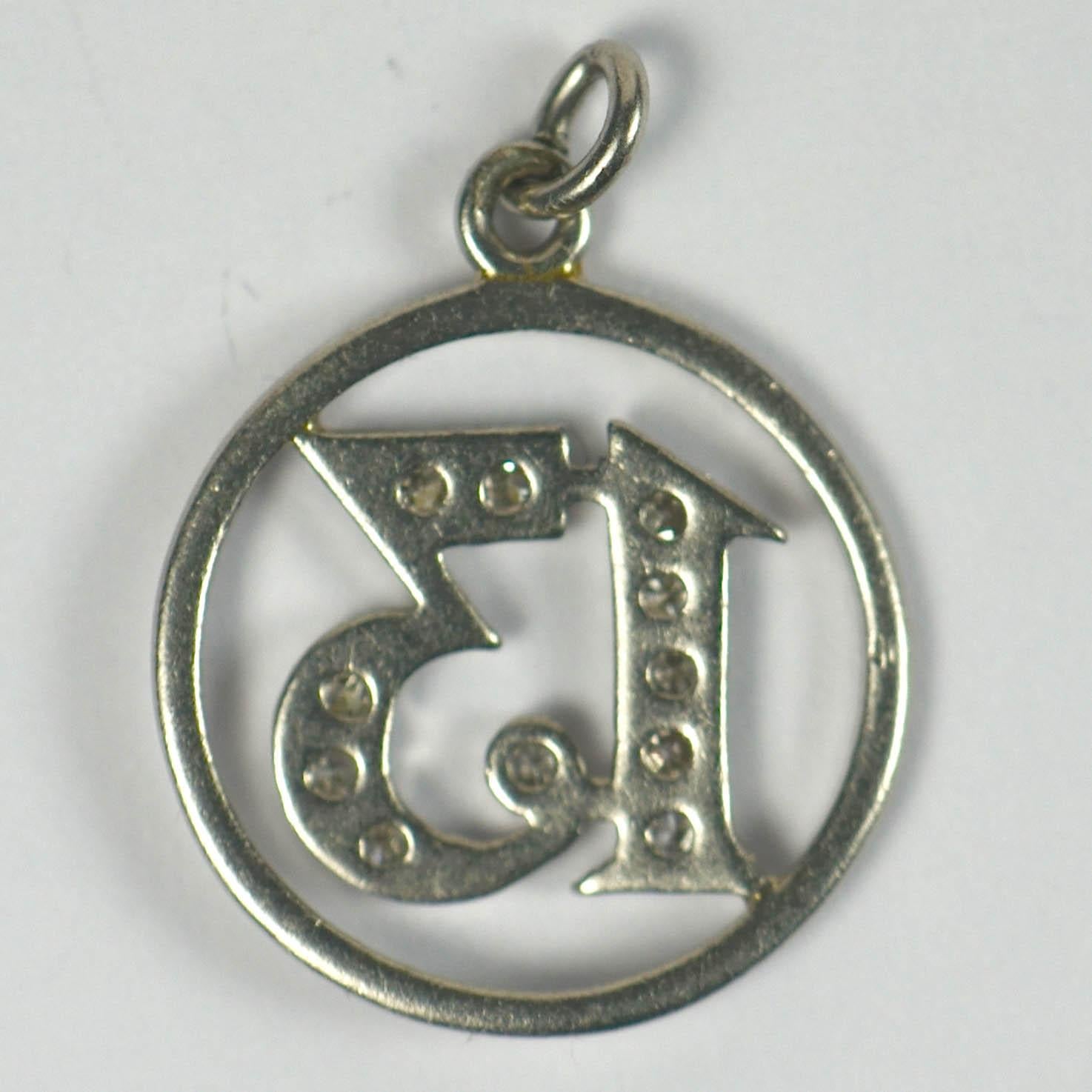 A platinum charm designed as a circle with a diamond set lucky 13 to the centre. 1/2