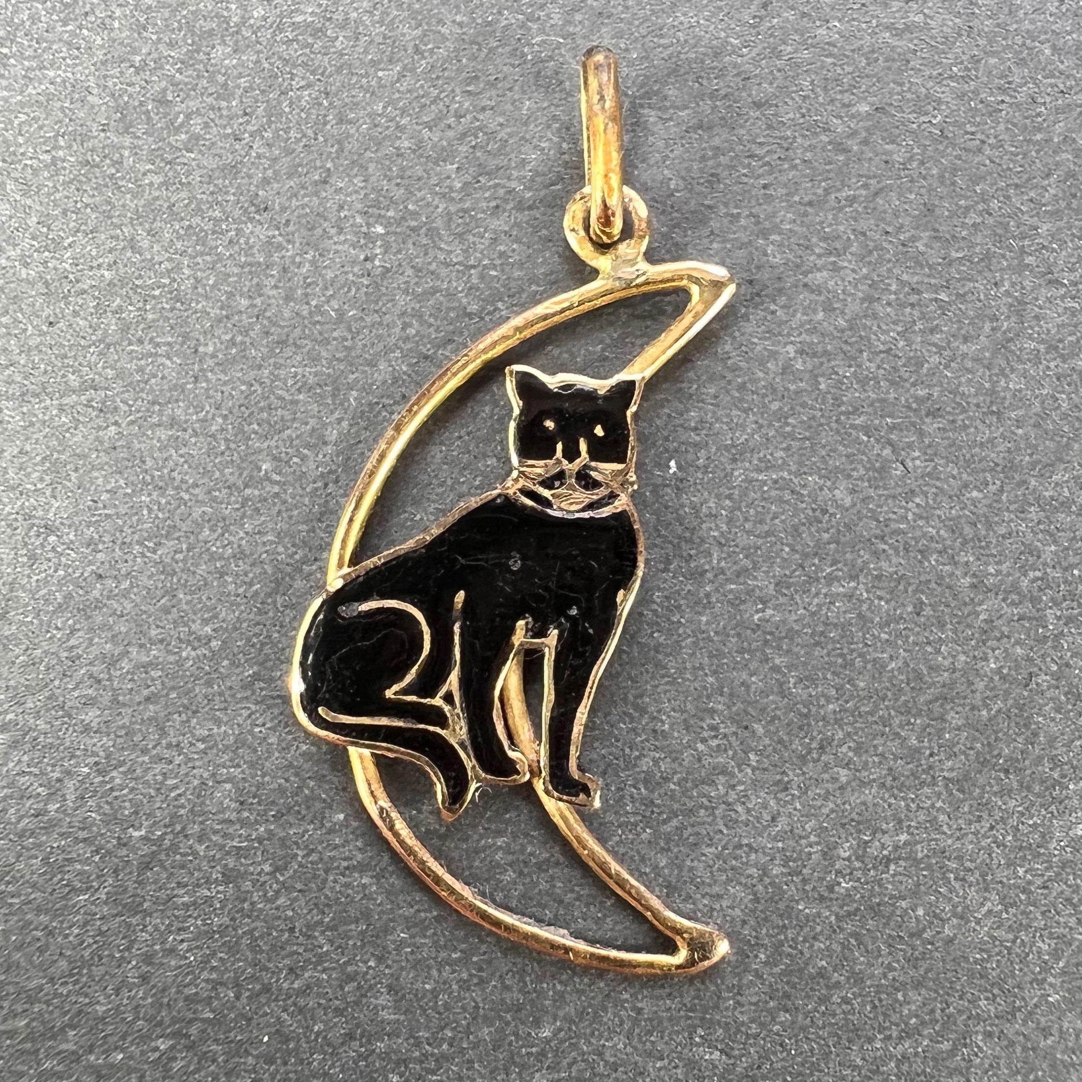 Un pendentif de charme en or jaune 18 carats (18K) conçu comme un croissant de lune en fil de fer avec un chat en émail noir assis dedans. Estampillé de la tête d'aigle pour l'or 18 carats et la fabrication française.

Dimensions : 2.4 x 1,4 x 0,15
