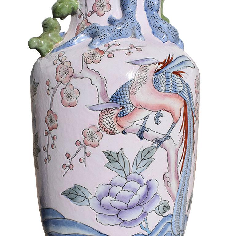 A tall chinoiserie famille rose vase with a floral and bird motif. This gorgeous ceramic vessel will be fabulous on a center table, side table, or in a foyer on a credenza. The neck of the vase is fluted with a scalloped rim and features two foo