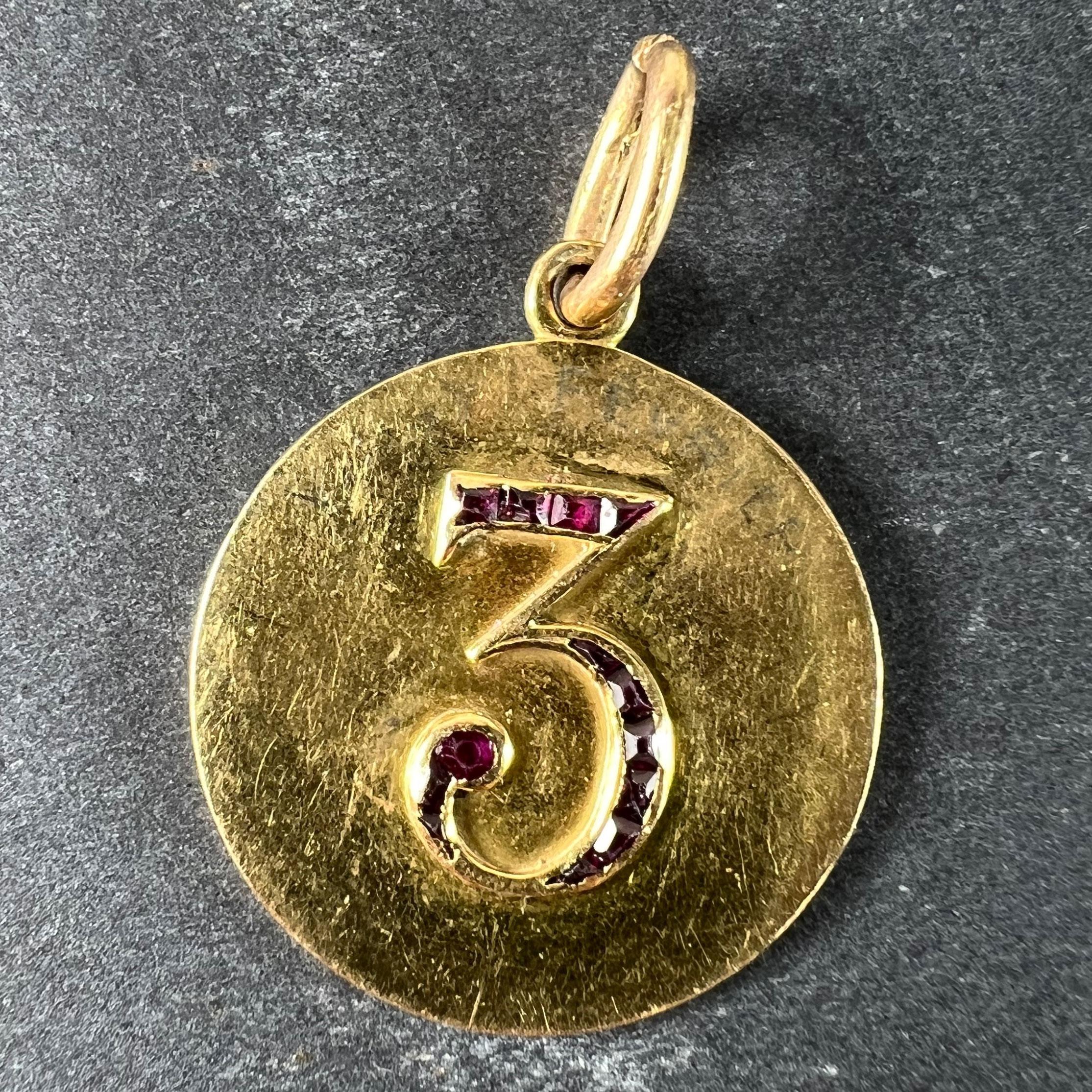 An 18 karat (18K) yellow gold good luck charm pendant designed as a lucky ruby 'Number 3' in the centre of a gold medal or disc, the number '3' set with (lucky) 13 fancy baguette-cut red rubies. Unmarked but tested for 18 karat gold. 

The number