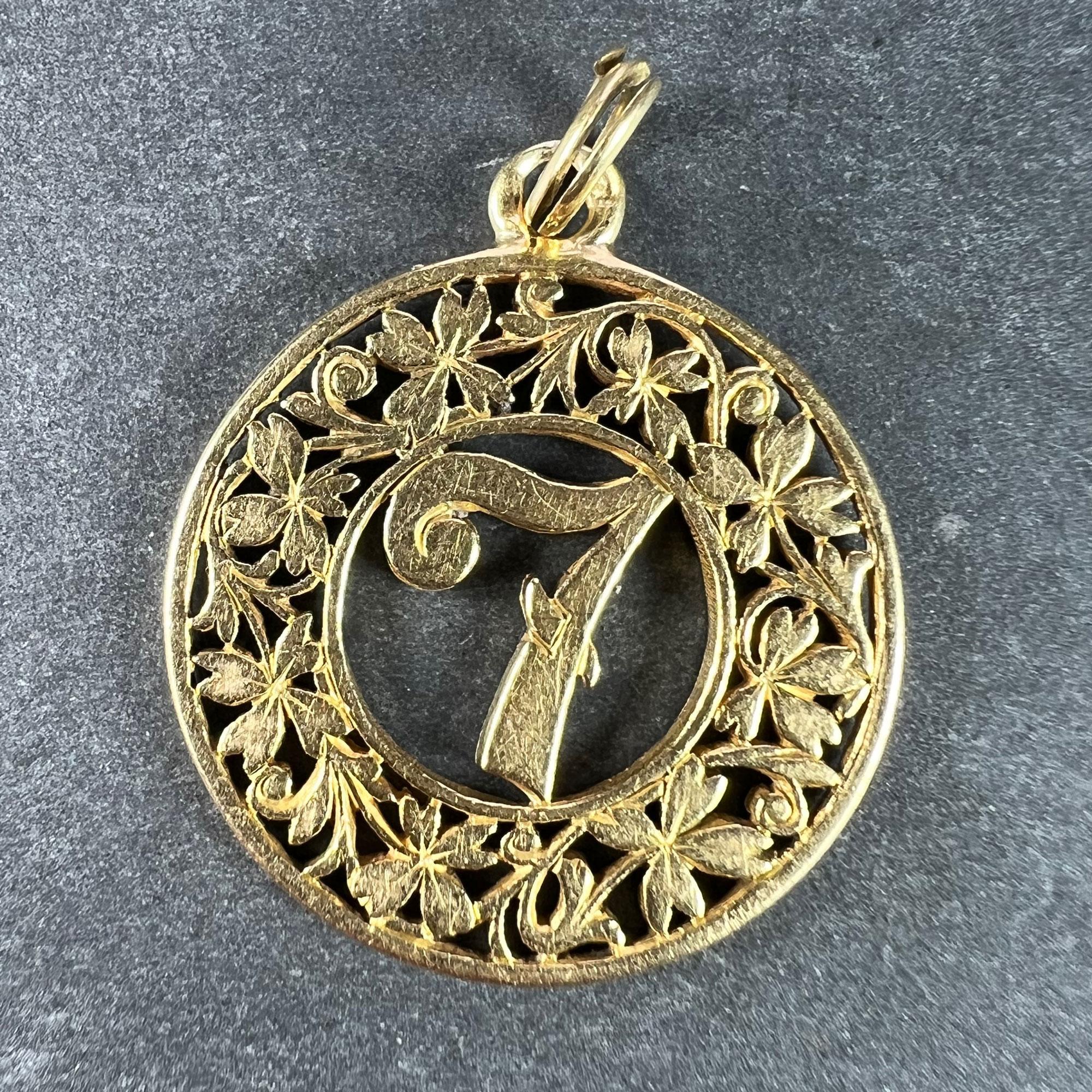An 18 karat (18K) yellow gold good luck charm pendant designed as the lucky 'Number 7' in the centre of a pierced wreath of four leaf clovers or shamrocks. Stamped with the owl mark for French import and 18 karat gold. The spring ring stamped with