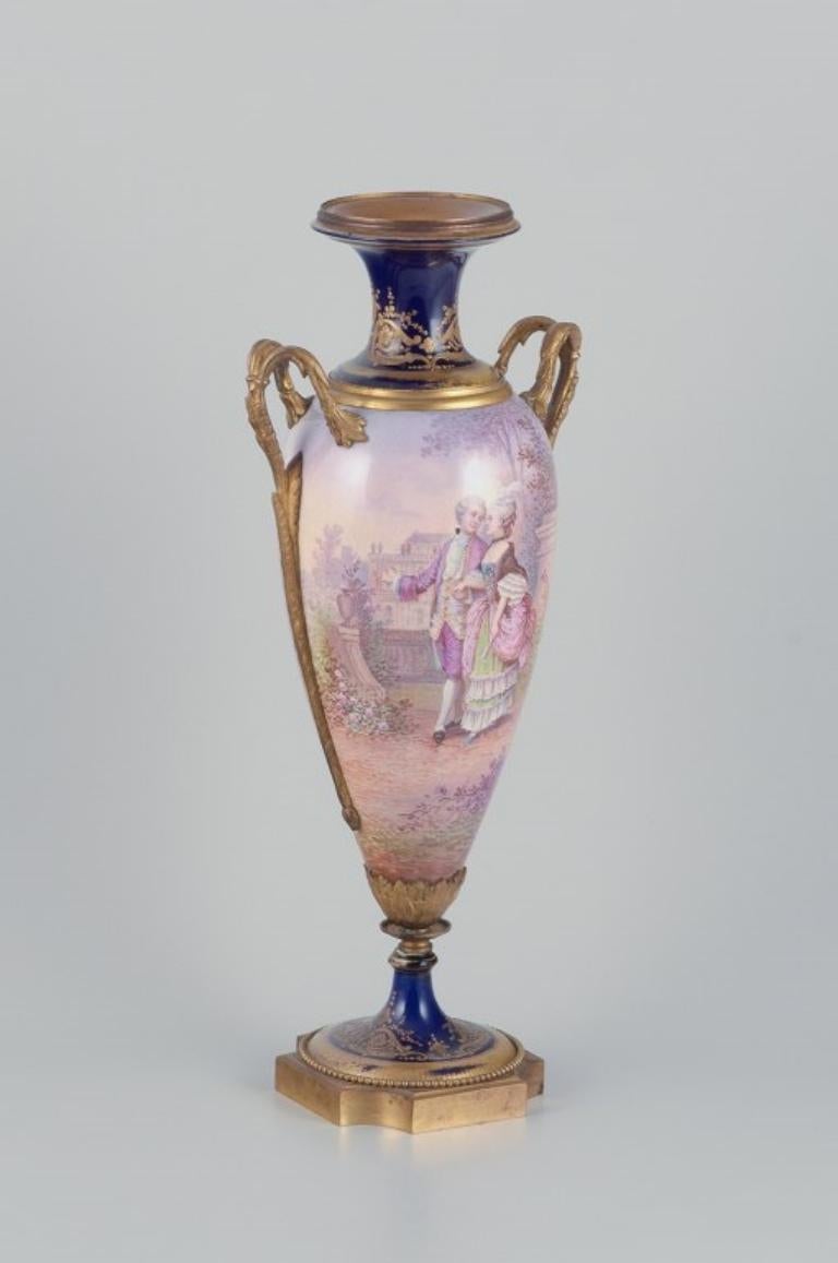 Lucot per Sèvres, Francia.
Vaso grande a forma di Amphora
 in maiolica e bronzo. Decorazione Sèvres Bleu con accenti dorati. Scena Galante. Dipinto a mano.
Firmato da Lucot.
Fine del XIX secolo.
In ottime condizioni con minimi segni di