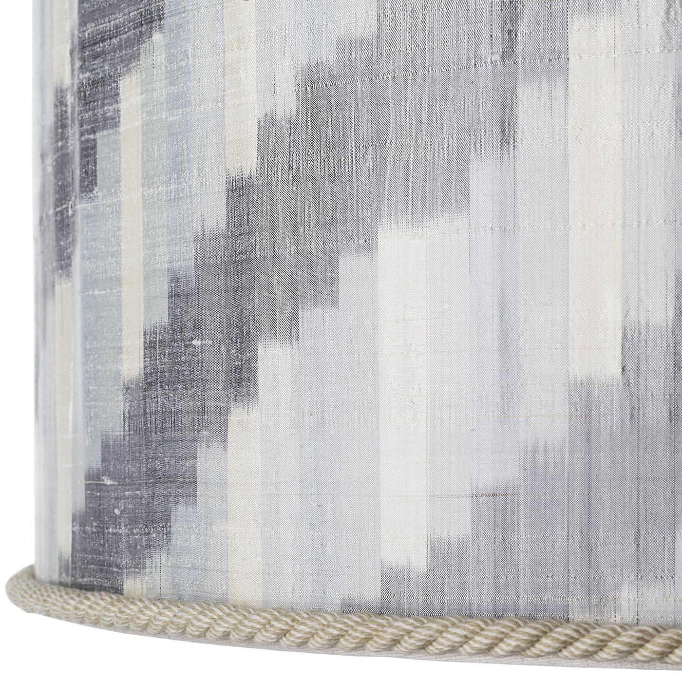 This sophisticated ceramic table lamp with a round base is characterised by even grooves that run horizontally along of its body, which is decorated with a platinum finish that gives it an almost otherworldly feel. Complete with an equally unique
