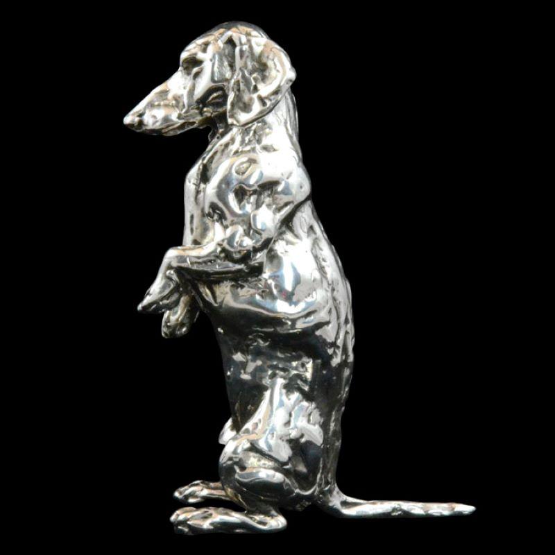 A 'Seated Dachshund’ sterling silver sculpture by Lucy Kinsella, the limited edition finely modelled dachshund sat up straight on his hind legs begging for a tasty morsel. His long thin tail points straight out behind him as he waits patiently with