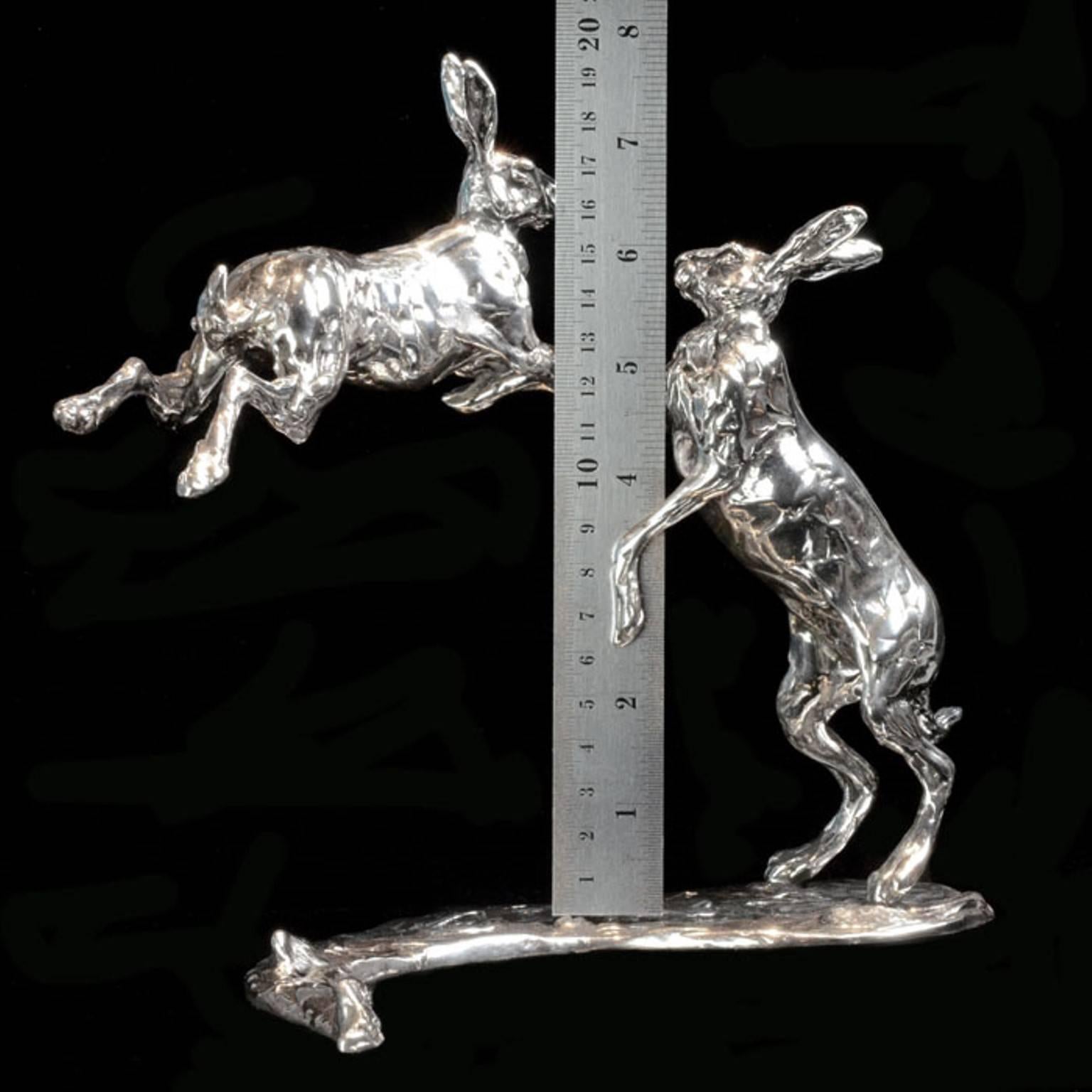 A ‘Leaping Hares’ sterling silver sculpture by Lucy Kinsella, the limited edition finely modelled pair of long eared hares caught mid confrontation with one stood tall on stretched hind legs, the other leaping through the air, front legs