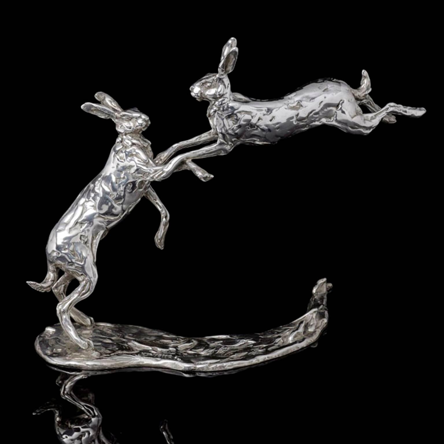 Una scultura in argento di Lucy Kinsella intitolata "Lepri che saltano", una coppia di lepri dalle orecchie lunghe finemente modellata che si scontrano: una si erge sulle zampe posteriori allungate, l'altra salta in aria con le zampe anteriori tese