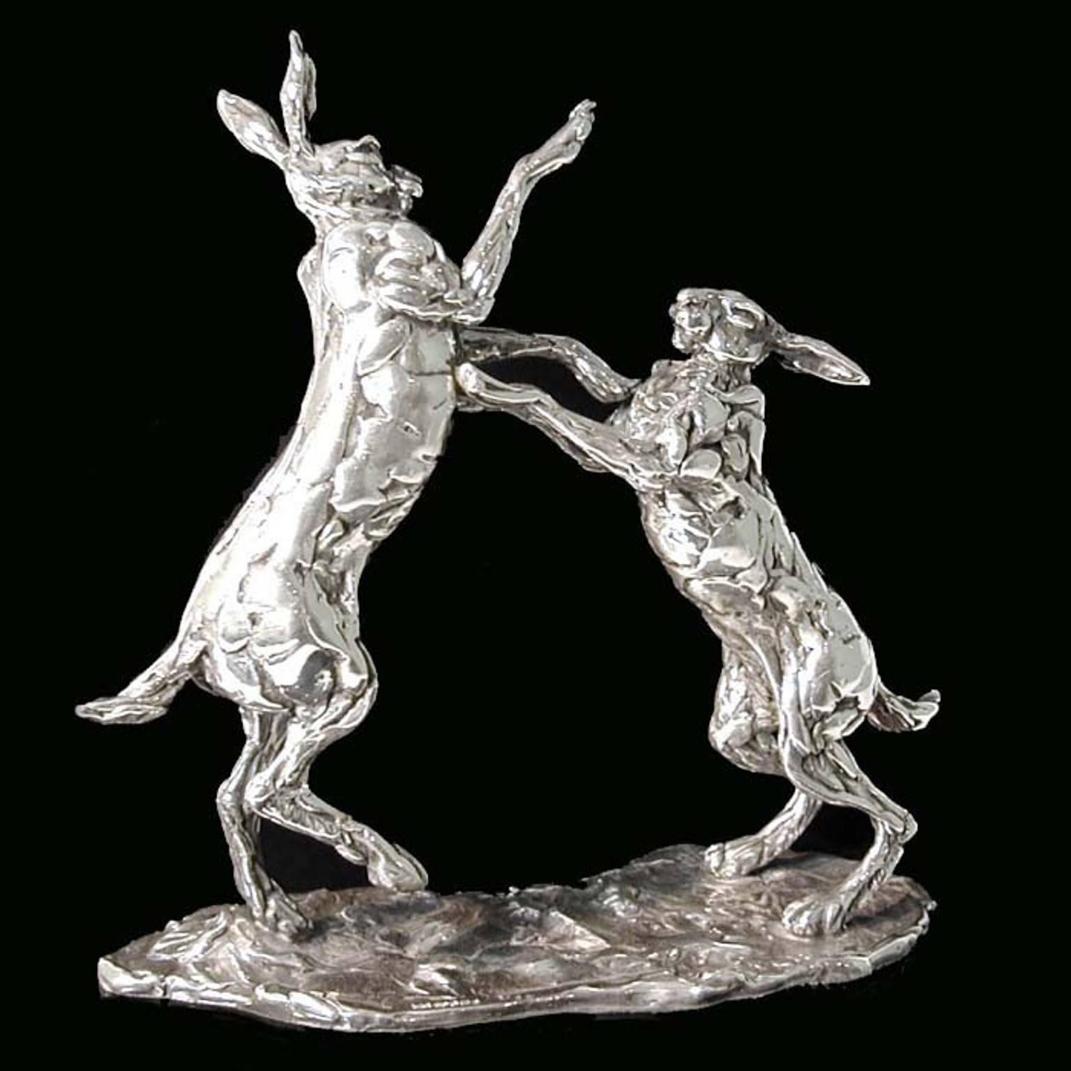 Height 20.5cm x length 20cm
1187 grams

A 'Boxing Hares' sterling silver sculpture by Lucy Kinsella, the limited edition pair of long eared brown hares caught mid boxing match, with one stood tall on stretched hind legs raining blows down on the