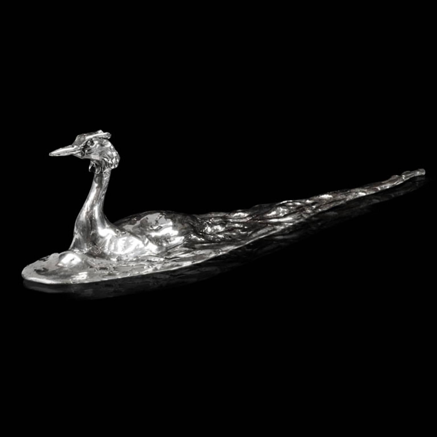A 'Great Crested Grebe' sterling silver sculpture by Lucy Kinsella, the limited edition finely modelled great crested grebe glides serenely through the gently rippling water, its long elegant neck stretched upright and head topped with elaborate