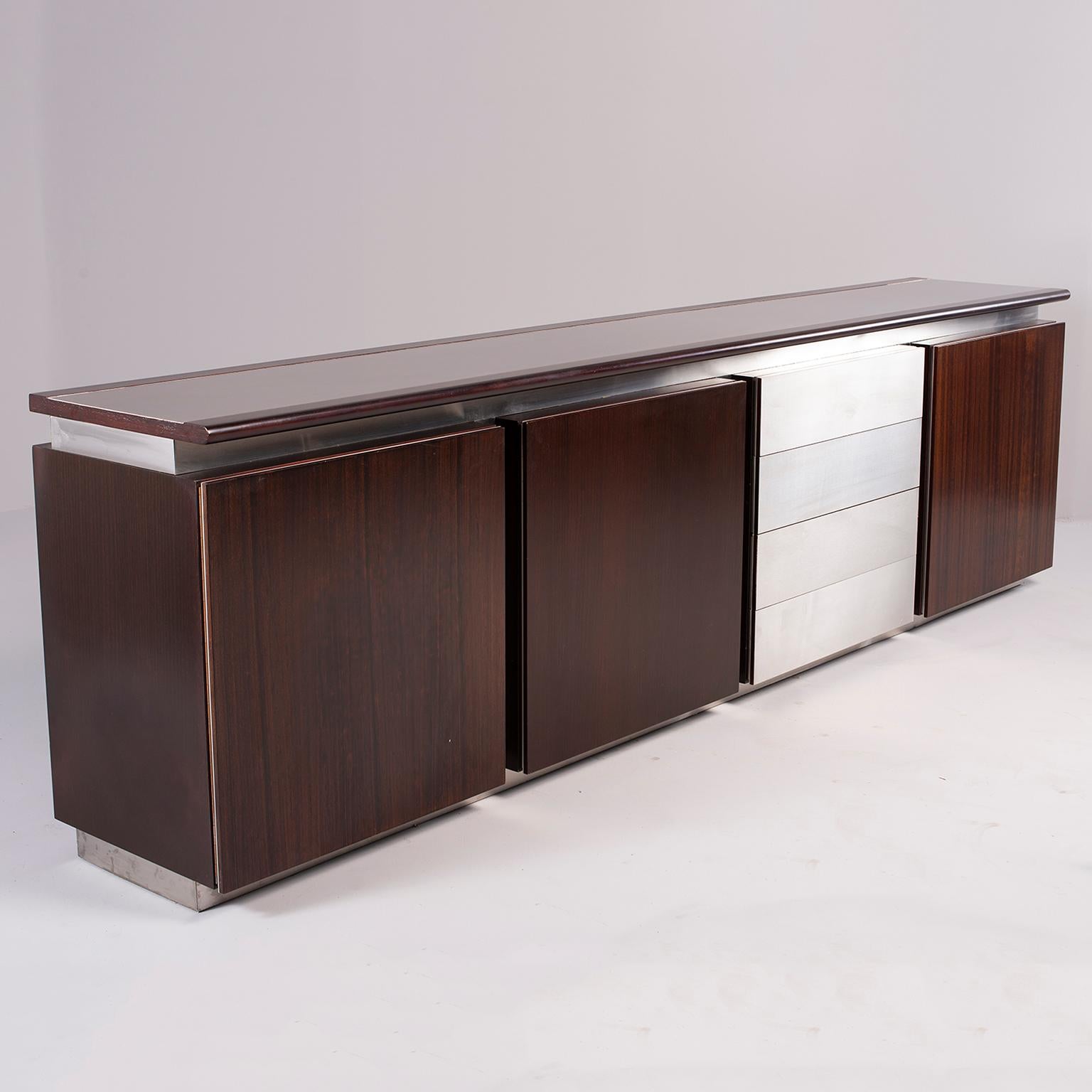 Sideboard or credenza designed by Ludovico Acerbis for Acerbis of Italy, circa 1970s. Dark rosewood with contrasting stainless steel trim and drawers. Three storage compartments with hinged doors and adjustable internal glass shelf and one set of