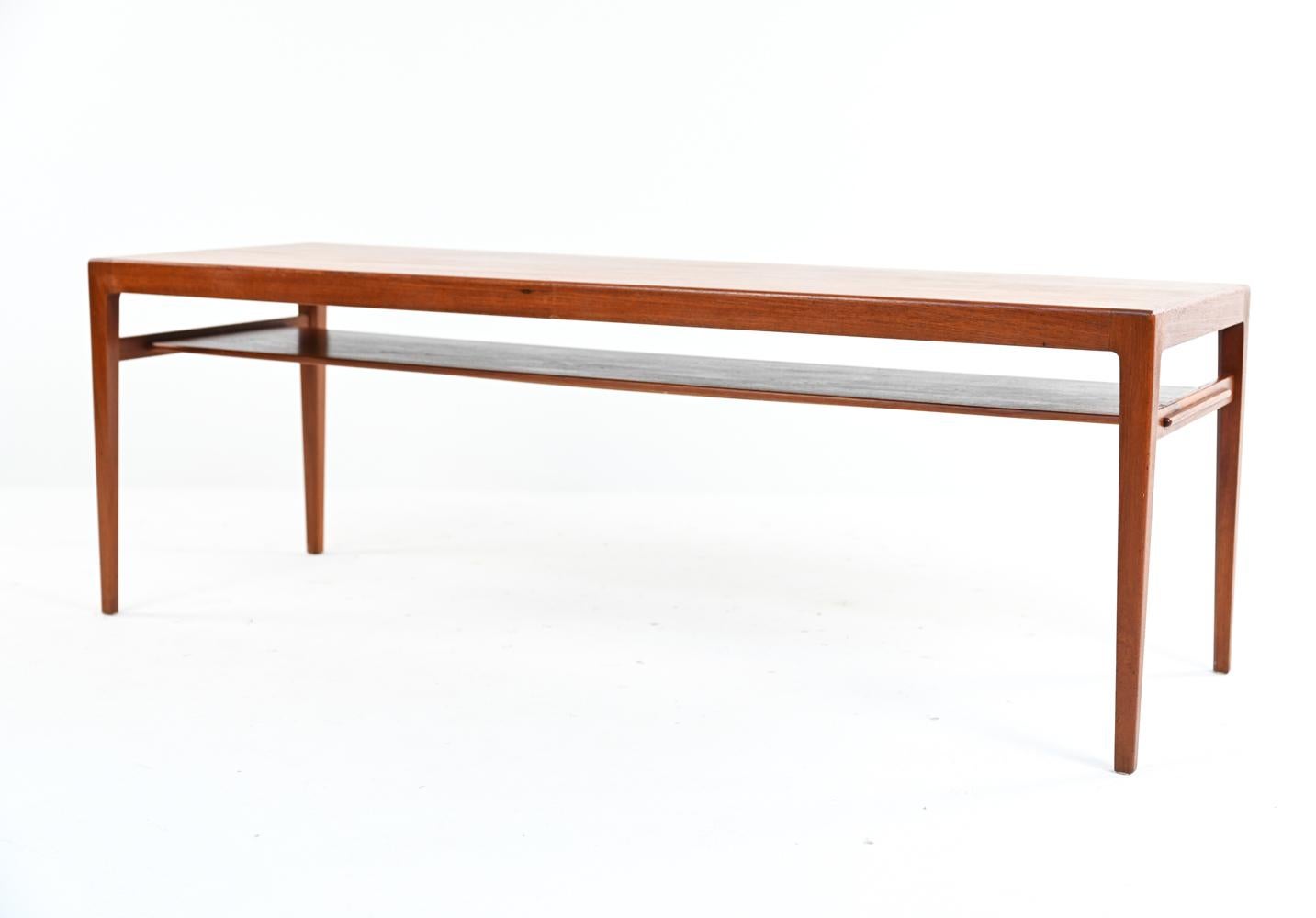A sleek, minimalist Danish mid-century two-tier coffee table designed and produced by Ludvig Pontoppidan, retaining original manufacturer's label underneath. Quality construction in teak wood featuring tapered legs.