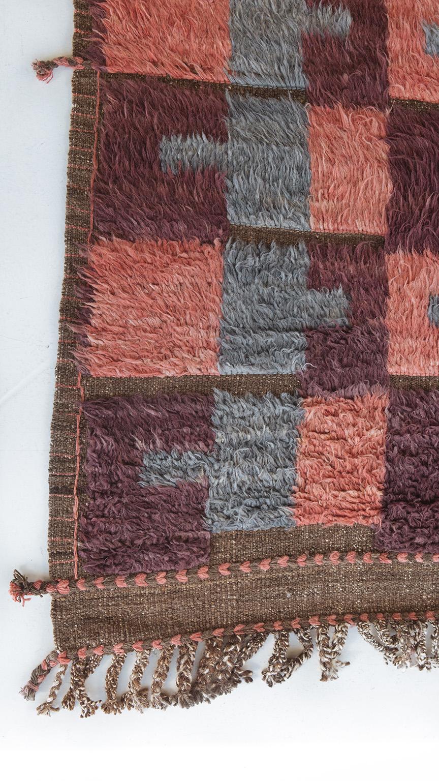Tapis à poils longs tissé à la main créant un motif répétitif sur toute la surface, incorporant un bleu-gris, un rose et un violet bordeaux. Inspiré par les éléments du design scandinave et recréé pour le monde du design moderne. Fabriqué avec soin,