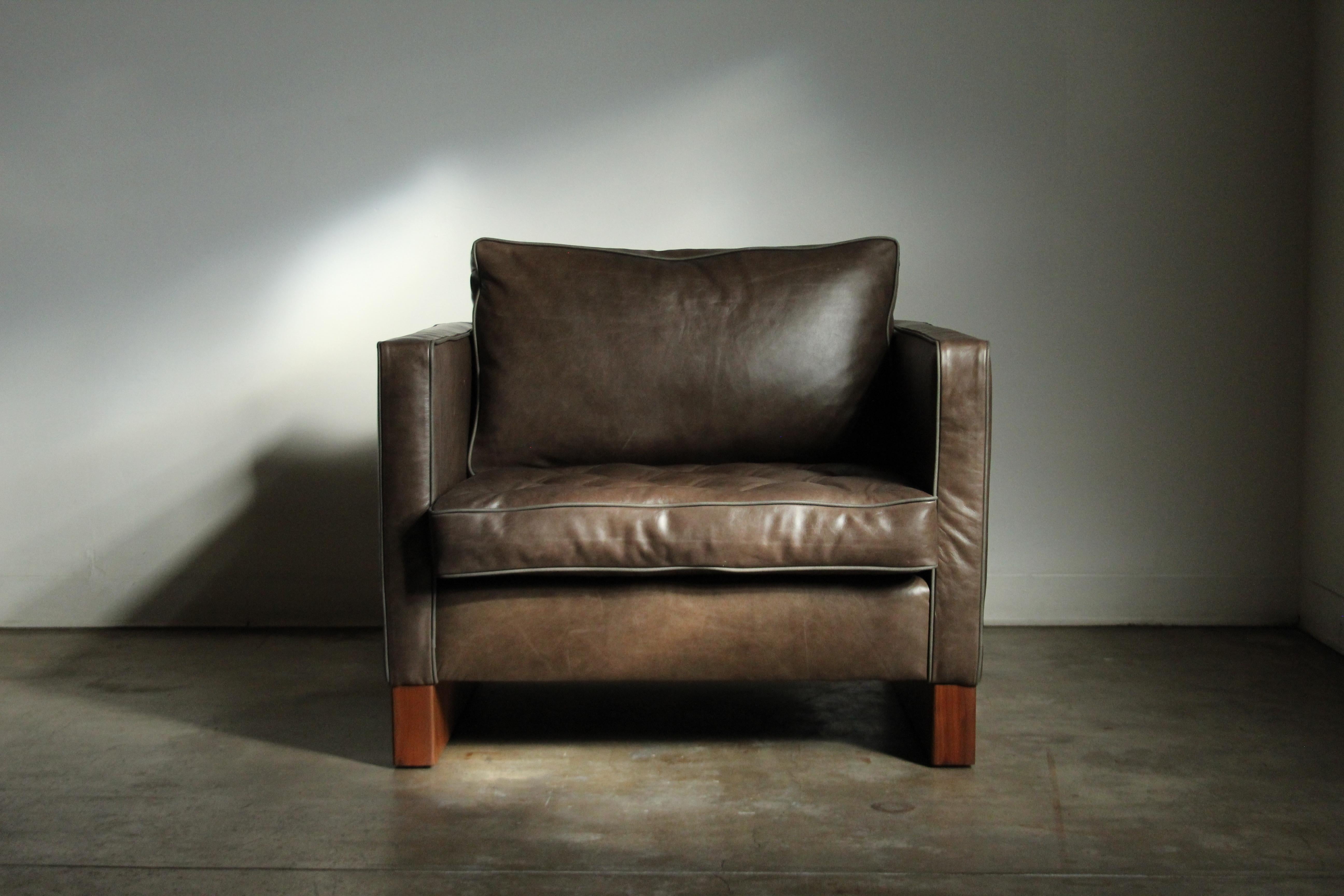 A large and very uncommon cube form lounge chair designed by Ludwig Mies van der Rohe and manufactured by Knoll in the 1940s. This big, sturdy chair is freshly upholstered in beautifully distressed gray-green leather and sits on two profound