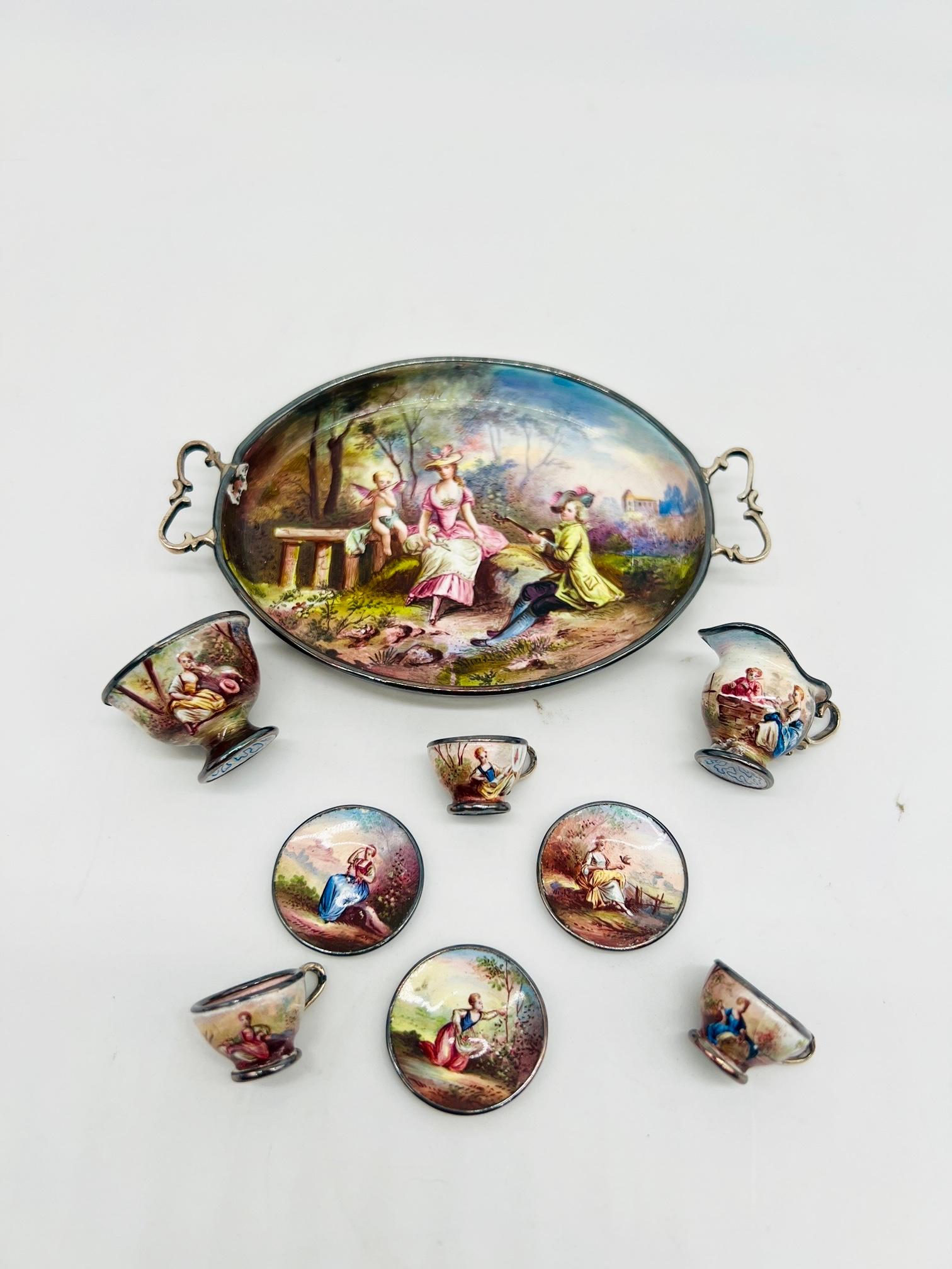 Ludwig Politzer (Vienna, 1841 -1907), 19th century.

This remarkable nine piece miniature tea service is quite rare and finely decorated. The set includes a double sided enamel tray featuring a courting scene with lush landscape to the top side and