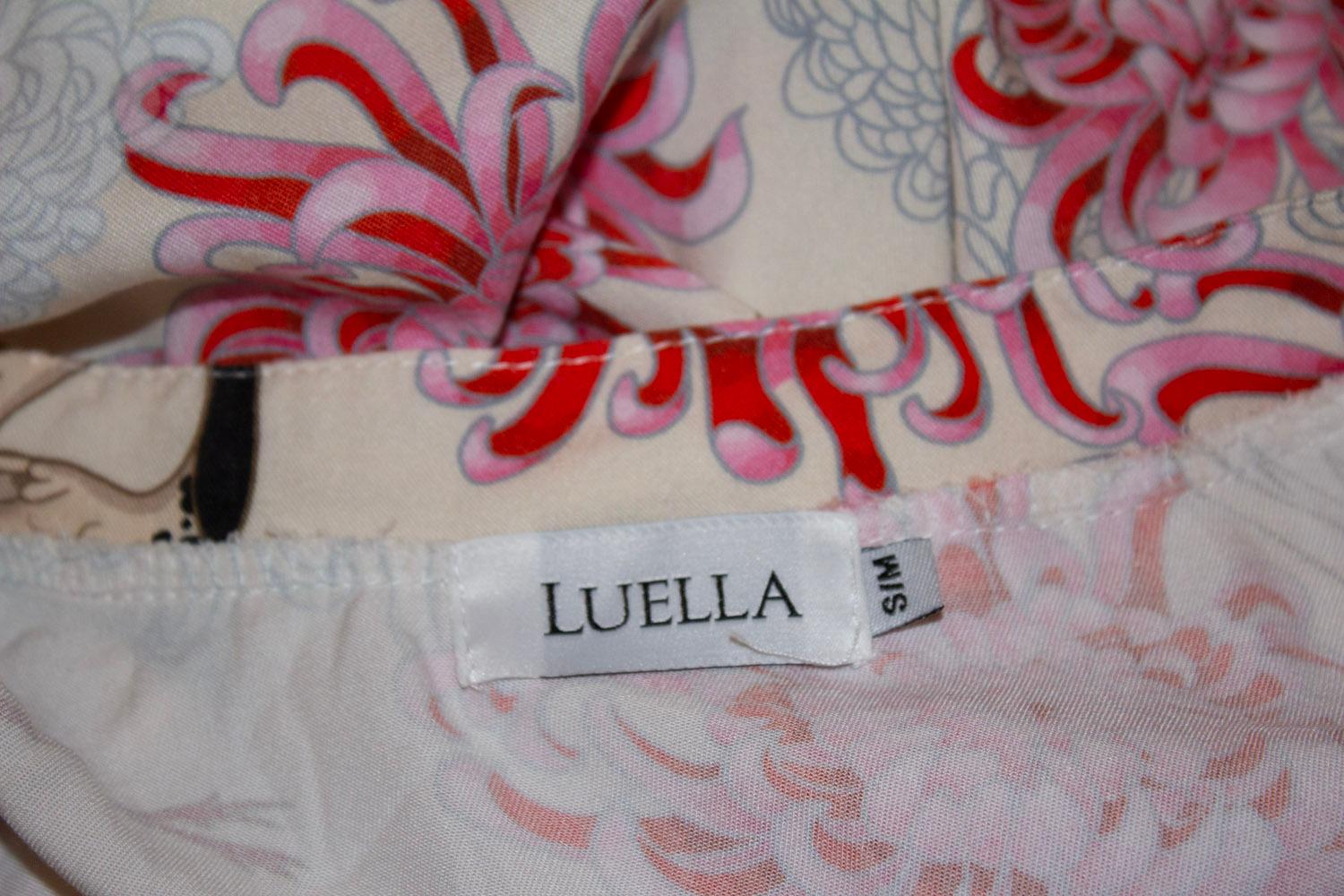 Un top tunica chic di Luella. Il topo ha uno sfondo avorio con una stampa rosa in stile orientale. Ha una scollatura a colletto e maniche arrotolate.
Dimensione  S.I.M. Misure Seno fino a 39'', lunghezza 36''.