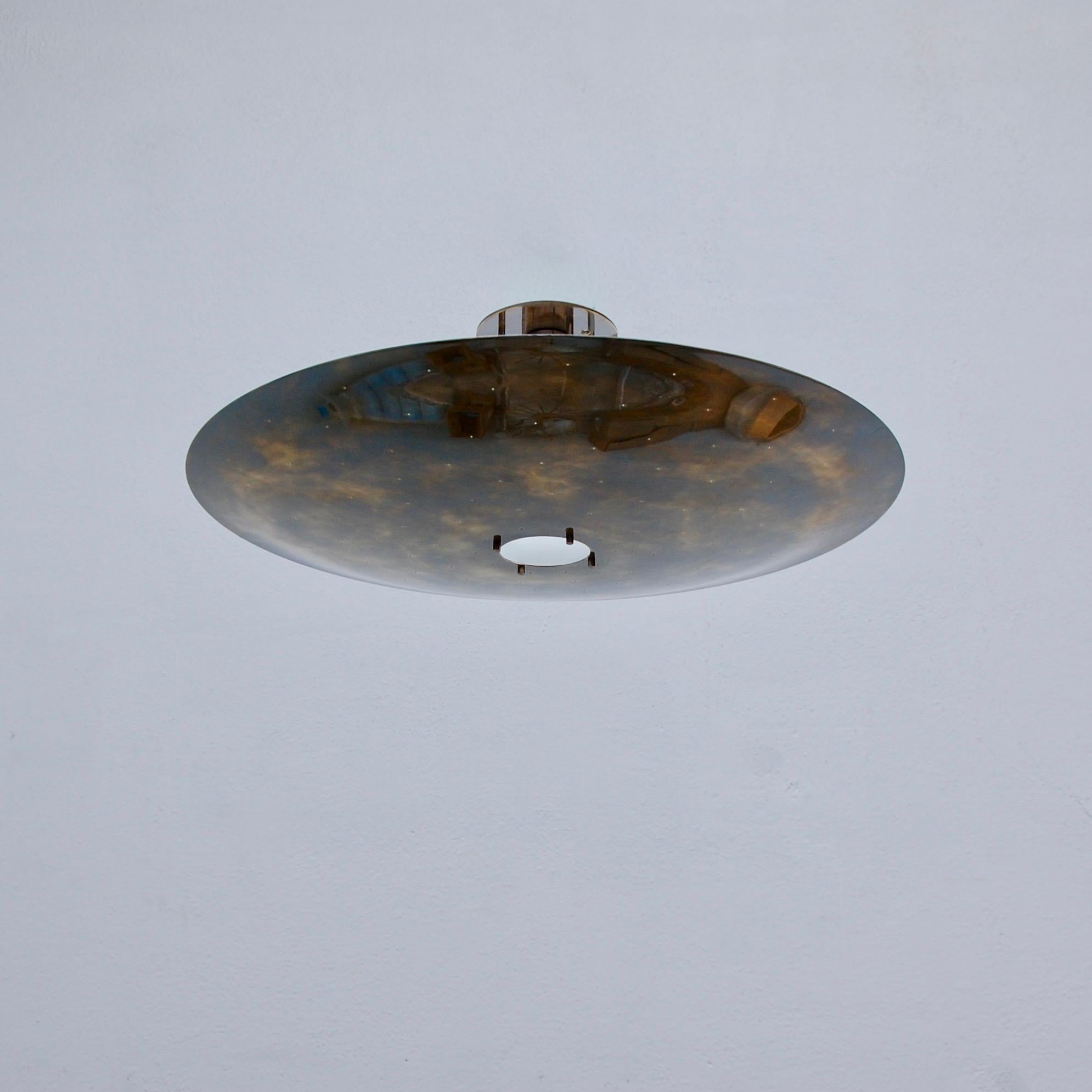 Plafonnier LUFO à dôme en laiton perforé de Lumfardo Luminaires. Faisant partie de notre collection contemporaine, le plafonnier LUFO est en finition patine foncée. Des perforations manuelles encadrent un trou central plus large avec un petit
