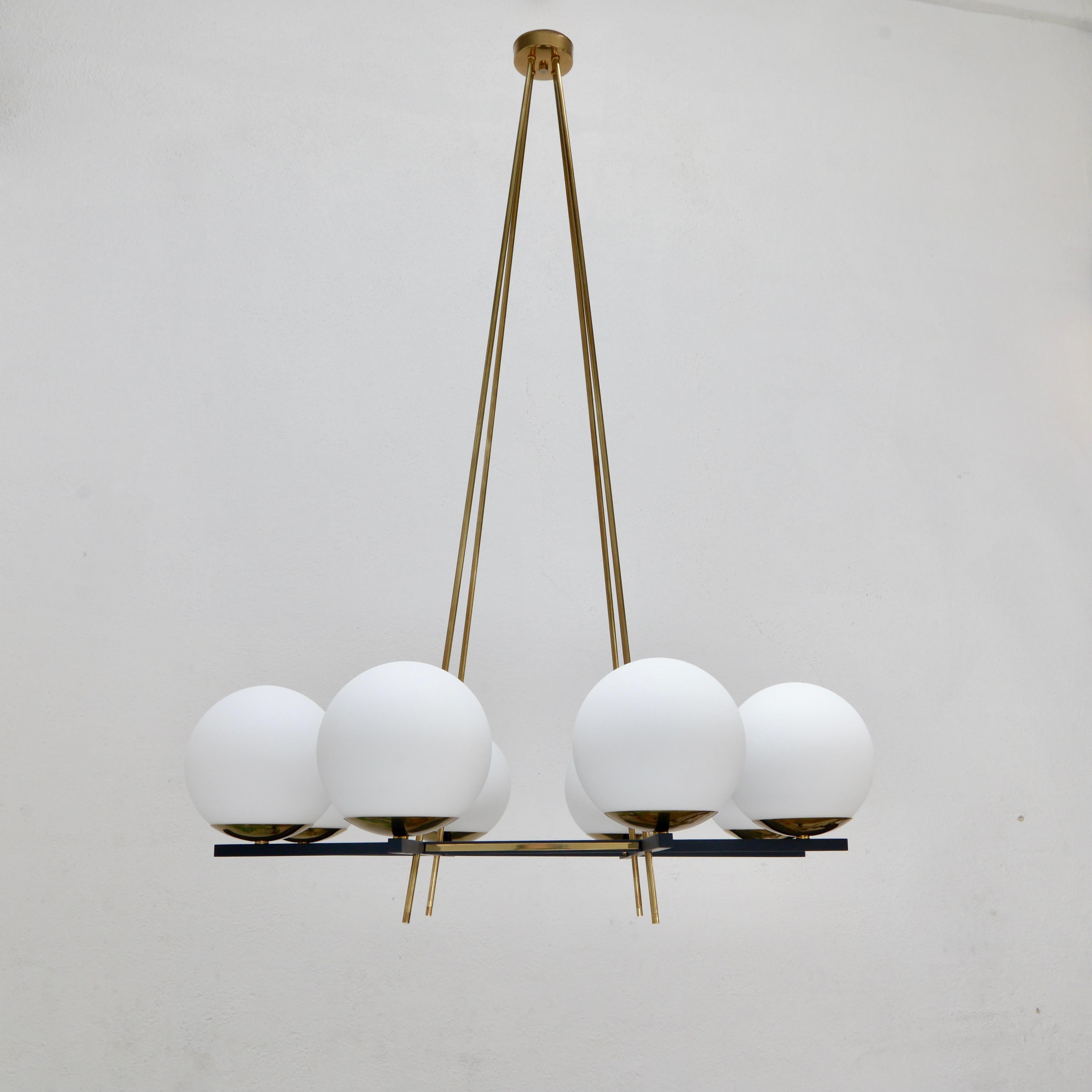 Stunning LUglo, an 8 globe glass shade chandelier inspired by classical mid century Italian design. Made in glass, steel, aluminum and aged brass. Featuring an elegant grid pattern, this chandelier is wired with 1-E12 candelabra based socket per