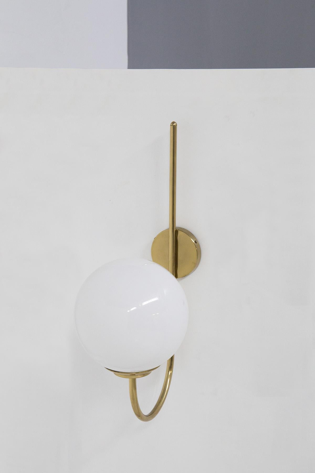 Splendid wall lamp designed by Luigi Caccia Dominioni in the 1950s for the Italian manufacturer Azucena.
The wall sconce has a beautiful and shiny gilded brass stem, which is attached to the wall by means of a round plate. From this springs a thin,