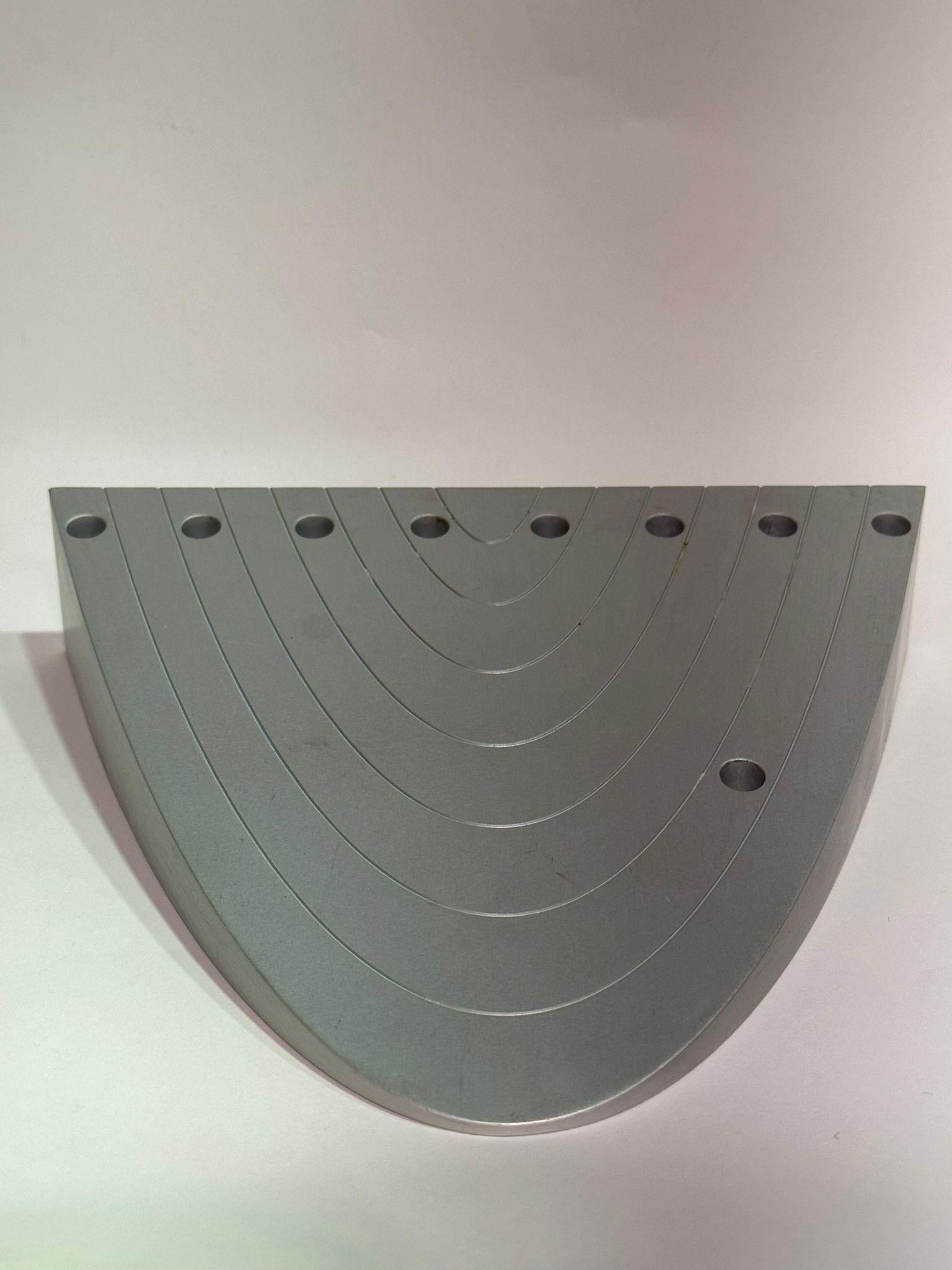 La lampe de Hanoukka de Luigi Del Monte, créée en 1999, est une réinterprétation saisissante de la ménorah traditionnelle de Hanoukka. Fabriquée en aluminium brossé, la lampe adopte un design minimaliste et moderne tout en honorant les traditions