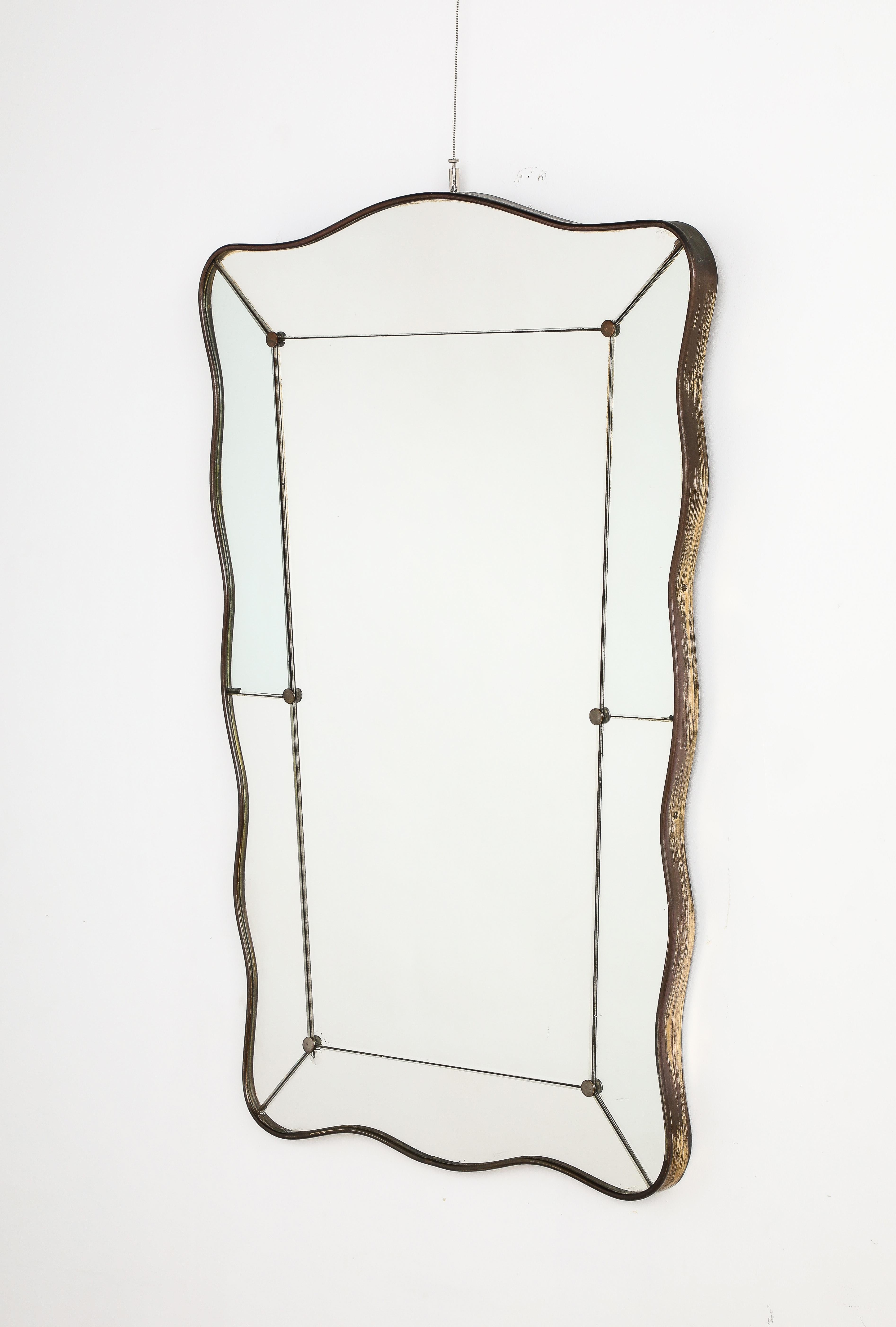 A wonderful scalloped shaped and slightly tapered brass wall mirror by the iconic mirror and glass design company Fontana Arte, Milan, circa 1940.  The rectangular inset glass panel is bordered by segmented mirror glass plates with metal posts;