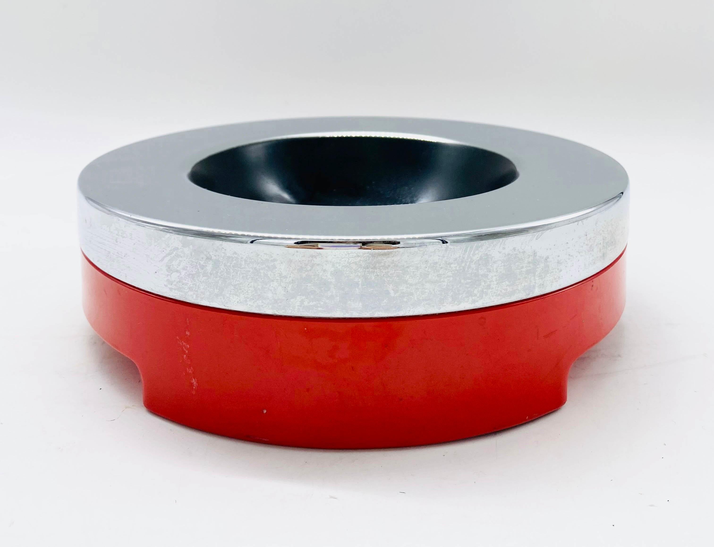 Incredible 6230 ashtray in chrome metal and red plastic. 
This wonderful piece was designed by Luigi Massoni and produced by Harvey Guzzini in Italy in the 1970s. 
The upper part of this item is made of chrome metal in like-new condition, as is