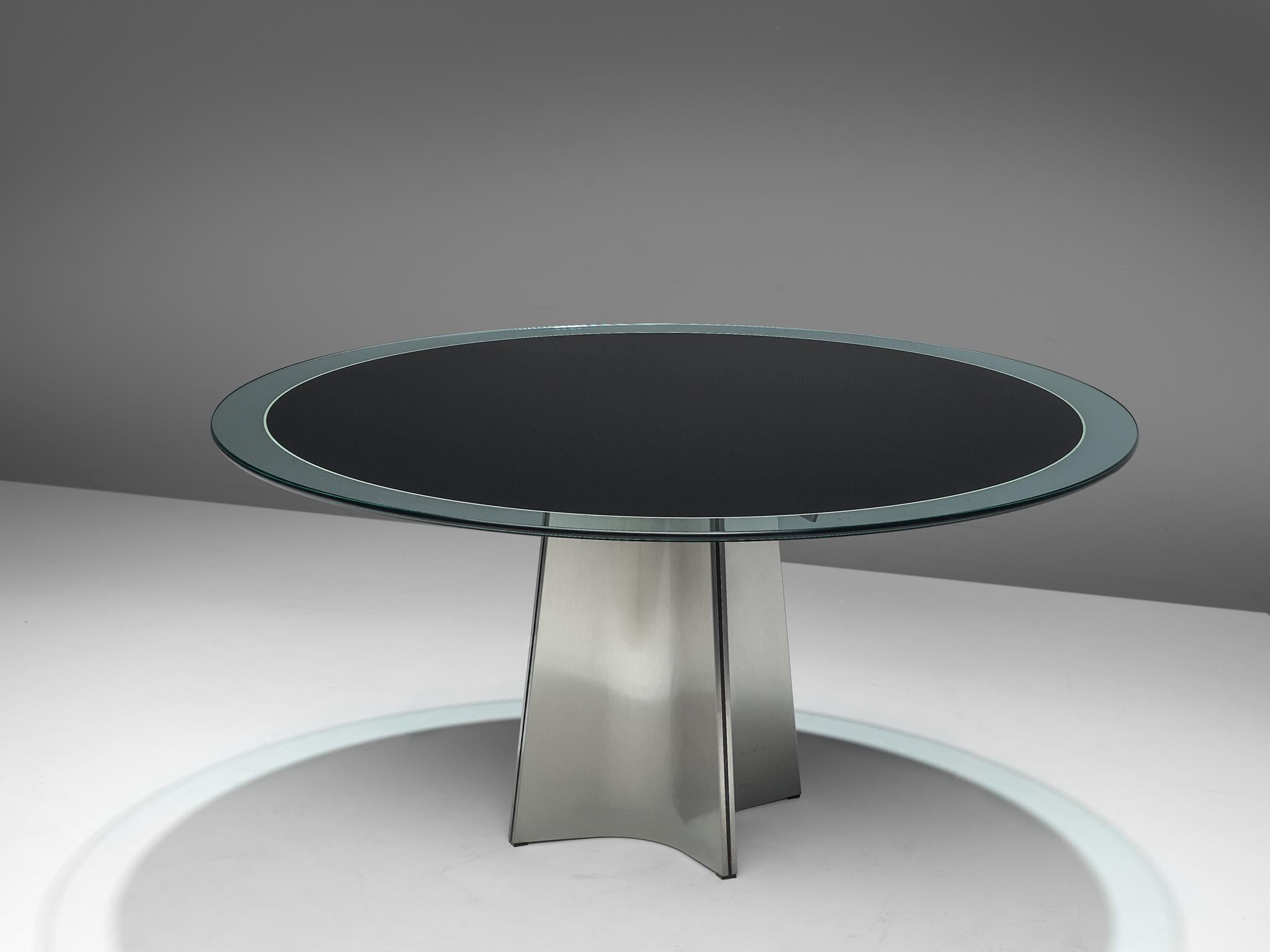 Luigi Saccardo for Armet, round dining table, glass and metal, Italy, 1970s.

Round pedestal dining table in brushed aluminum. A circular clear glass top, with a dark center. The base is formed of four concave curved plates of metal, which combine