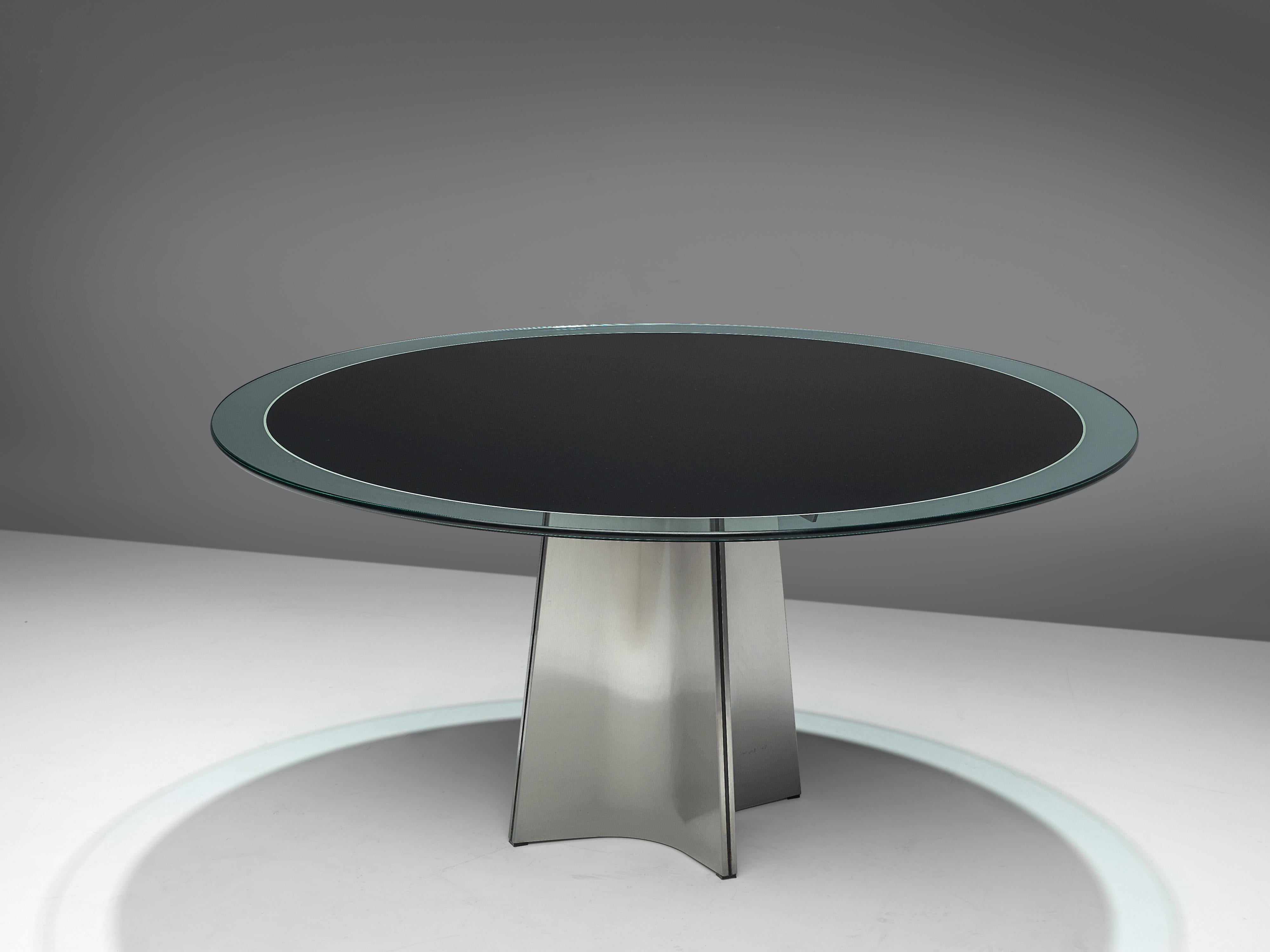 Luigi Saccardo for Armet, round dining table, glass and metal, Italy, 1970s.

Round pedestal dining table in brushed aluminum. A circular clear glass top, with a dark center. The base is formed of four concave curved plates of metal, which combine