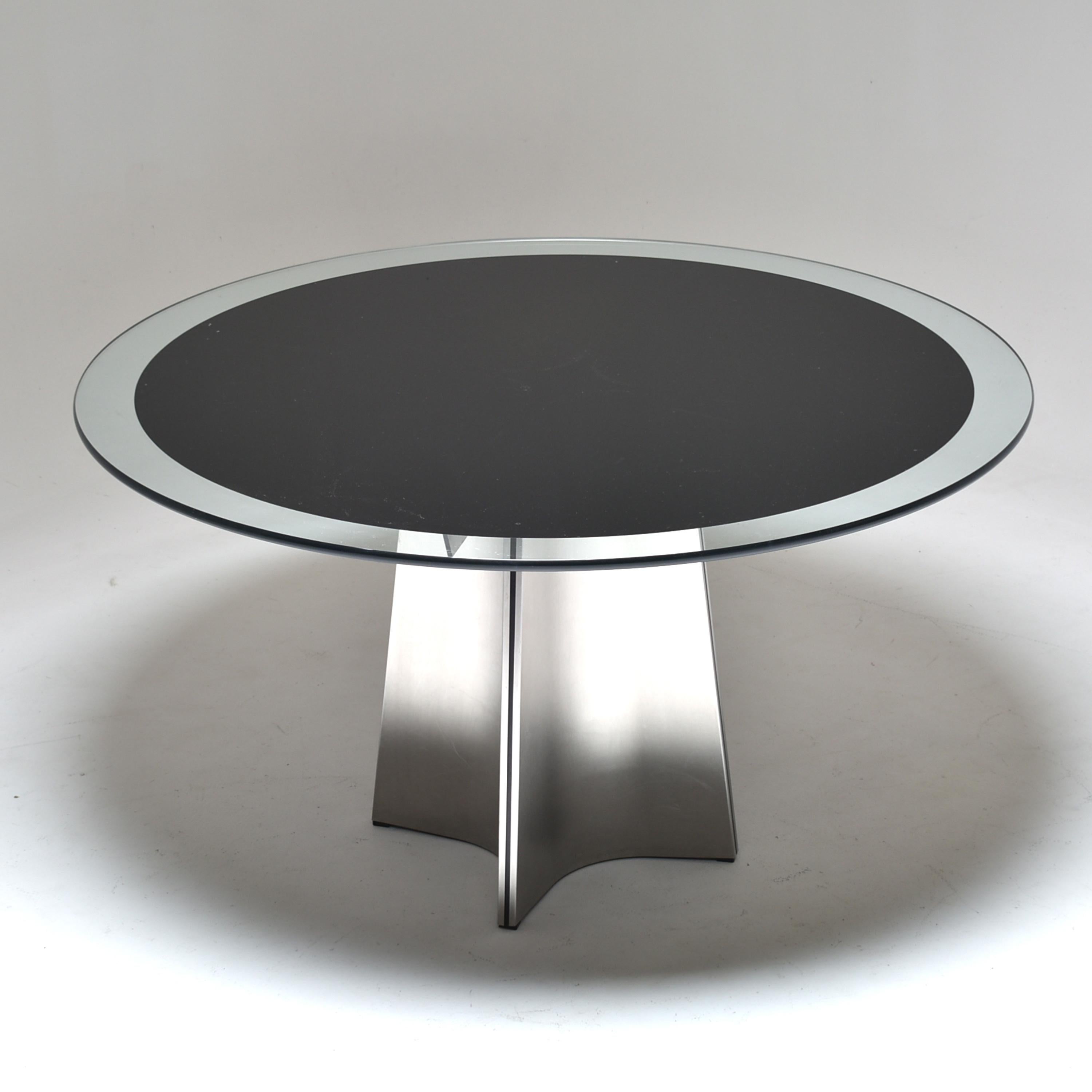 Round pedestal dining table, designed by Luigi Saccardo, for Armet, Italy, 1970.
The base is made of four brushed stainless steel plates, pressed to form a cross.
The top is a thick round clear glass, black lacquered (underside).
Very graphical