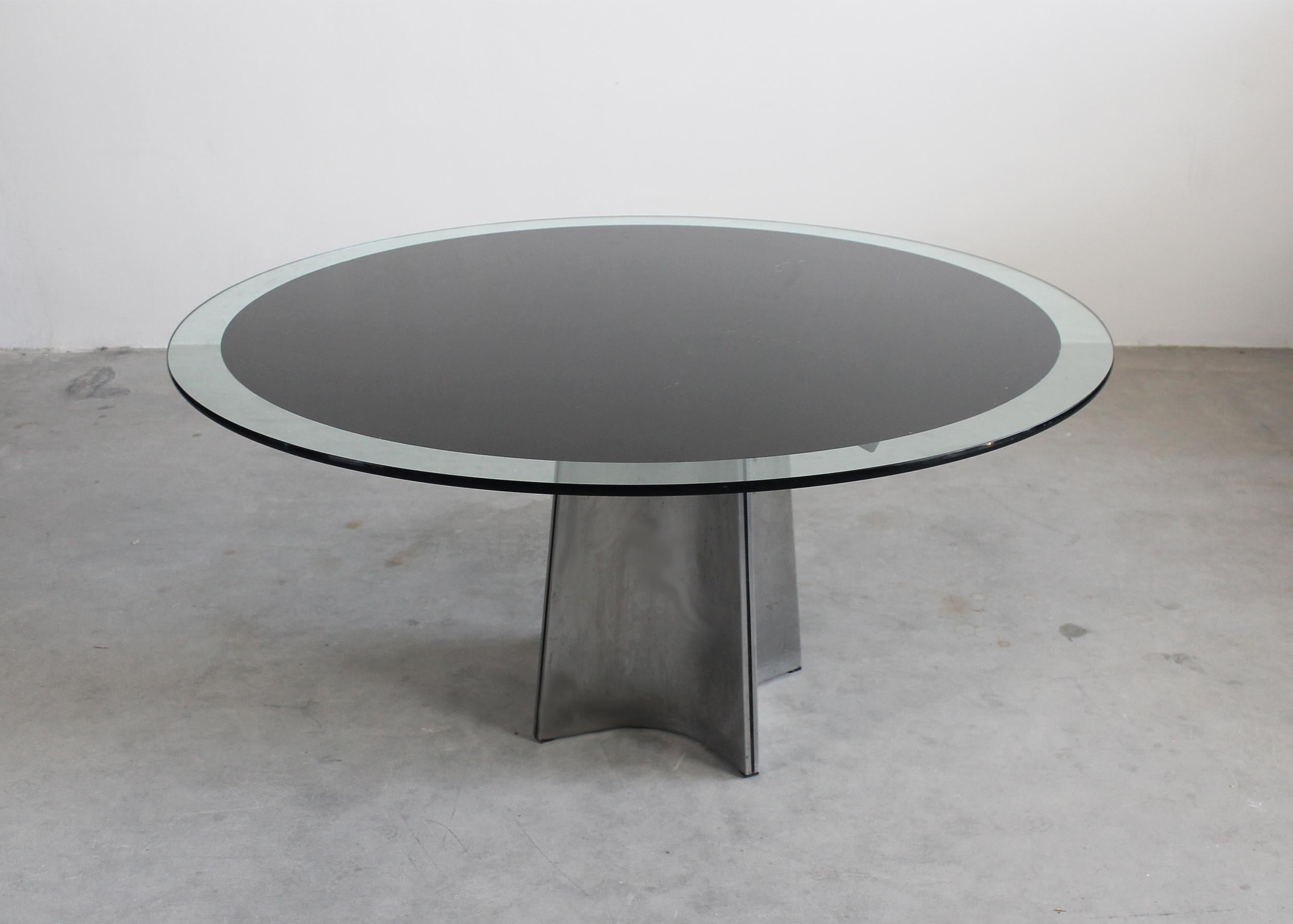 Table de salle à manger ronde à piédestal modèle UFO avec une base en acier brossé et un plateau en verre épais avec un cercle décoratif en émail noir. 

Conçue par Luigi Saccardo et fabriquée par la Maison Jansen dans les années 1970. 

La Maison