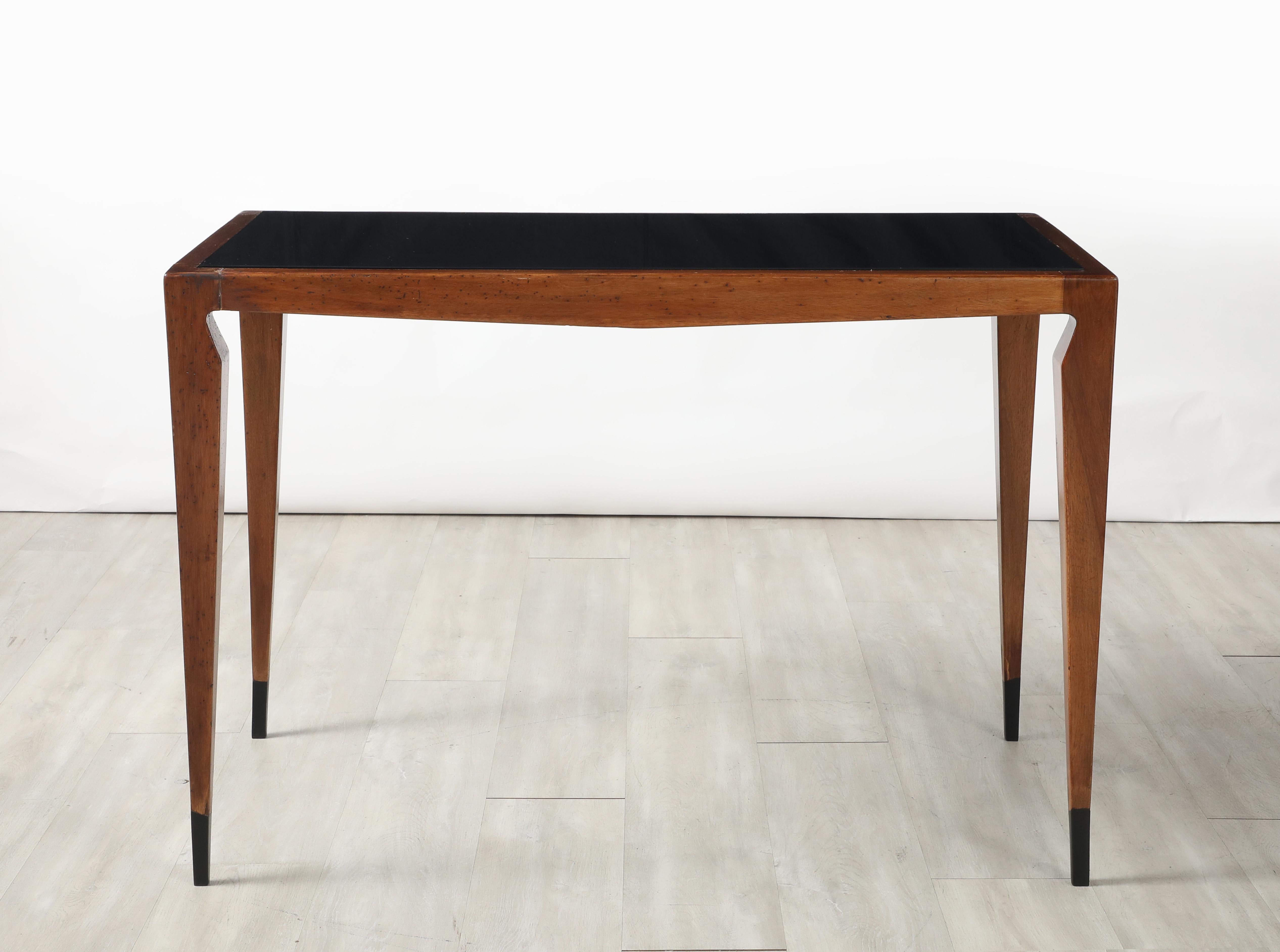 This console table displays the masterful craftsmanship and refined elegance of Italian design. Featuring a sleek and rich walnut construction its tapered legs with painted black-capped feet create a graceful, architectural silhouette.  The inset