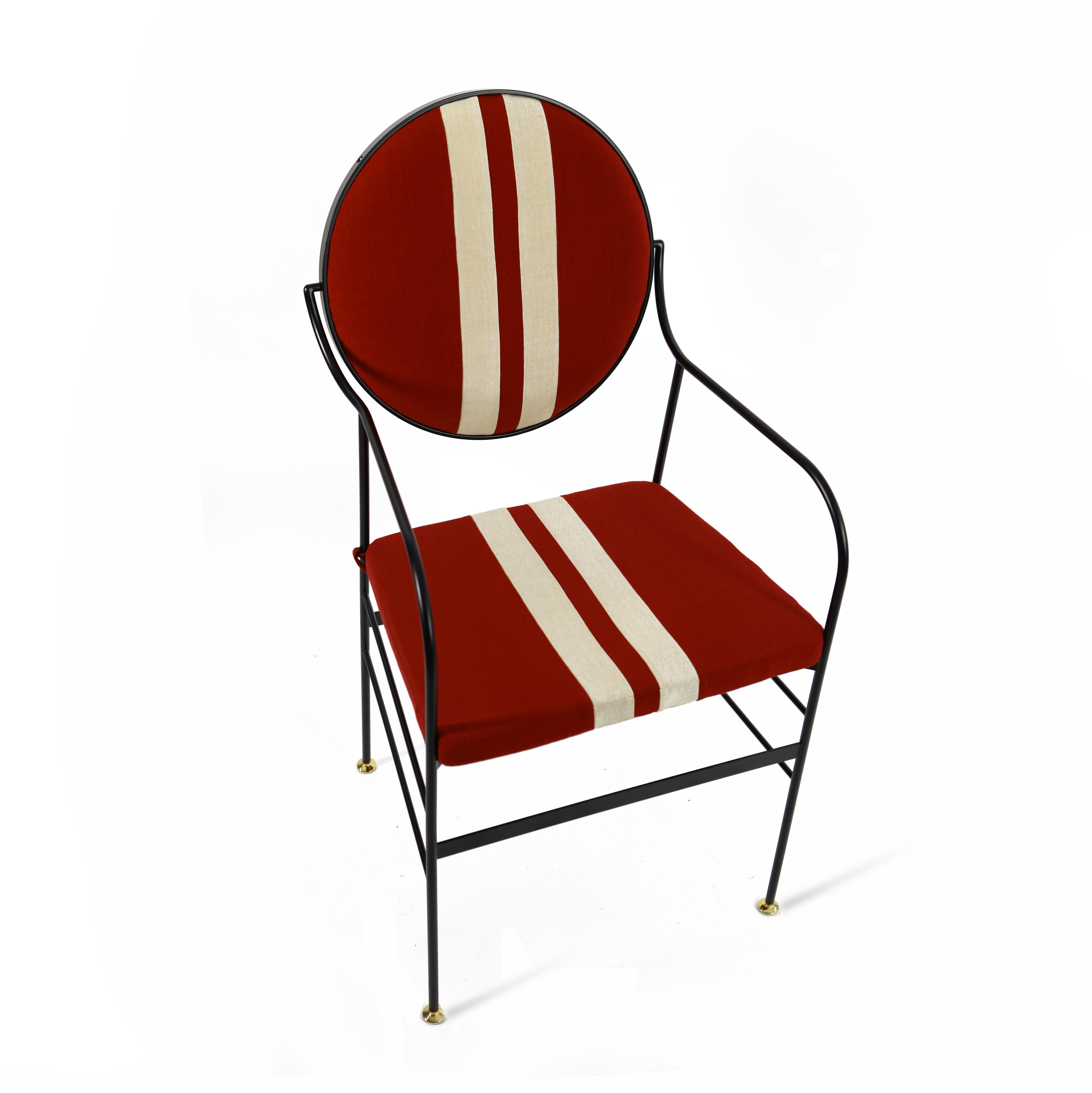 This striking chair is in iron with brass feet. The iron is dust painted and oven finished in matt black, while the back can rotate on its structure to achieve the perfect inclination. The fabric of back and seat is digital print to evoke the