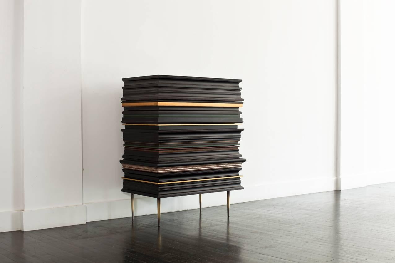 Frame dresser.
FRA-02 frame collection.
Design by Luis Pons.
Limited edition, signed and numbered.
Six drawers dresser featuring a walnut finish interior.
Antique bronze steel legs. Dark finish frame segments
with gold accents (shown in dark