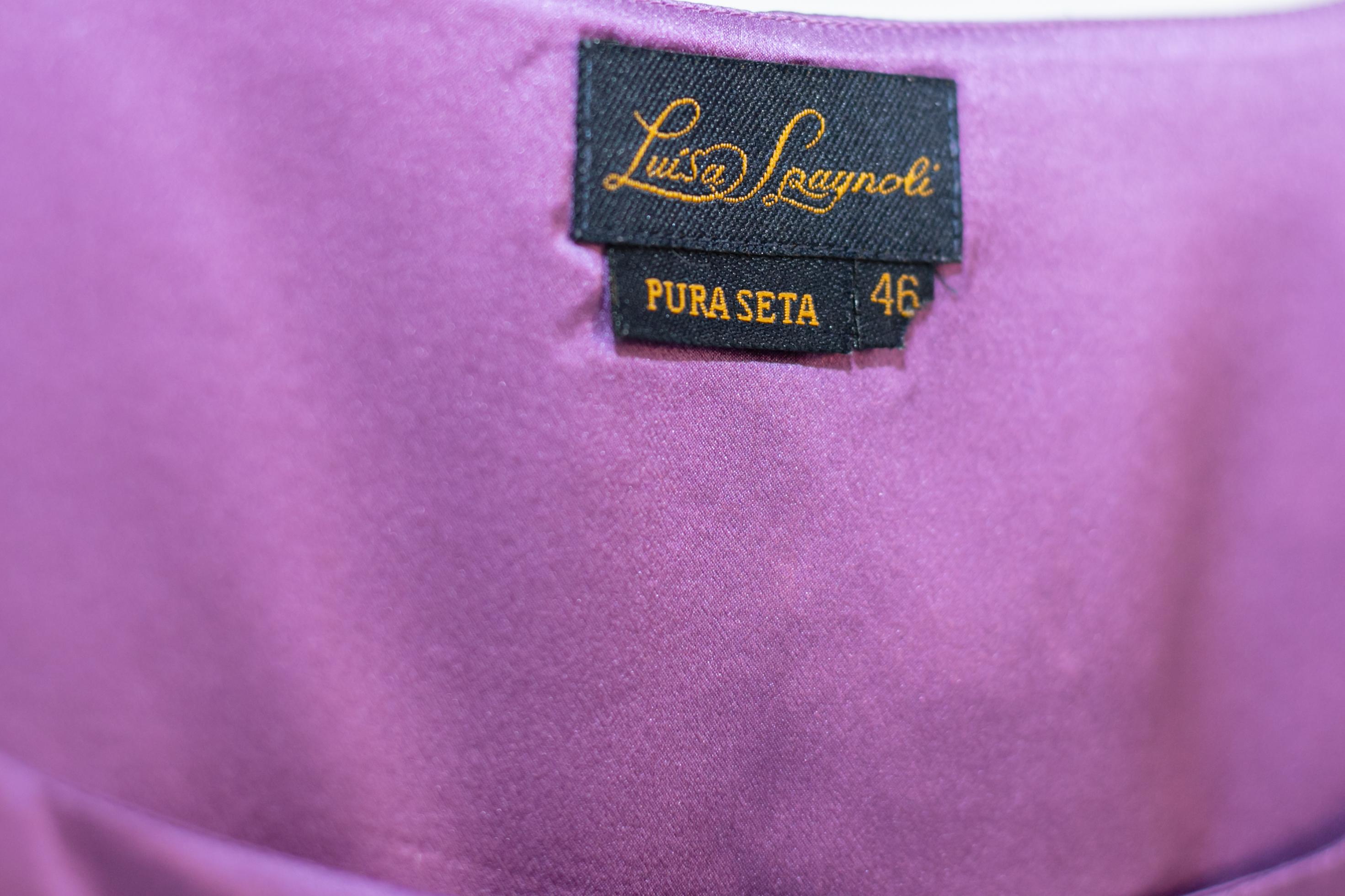 Colourful purple silk suit designed by Luisa Spagnoli in the 1980s, of fine Italian manufacture. ORIGINAL LABEL.
The dress consists of a classic, square neckline blouse with straps and a knee-length purple silk skirt with sweet flounces. Beautiful